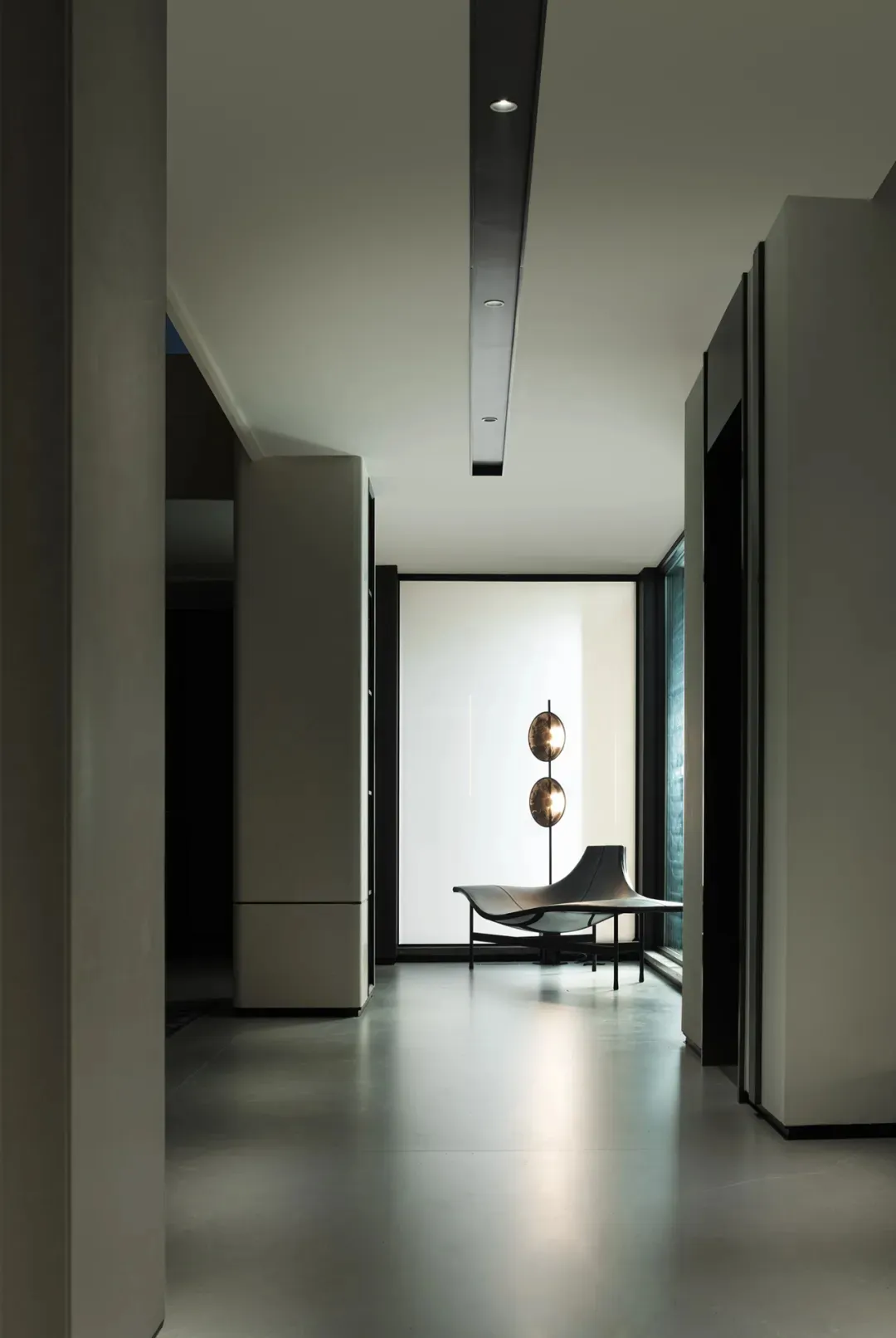 Modern lounge area with concrete walls and floor, featuring a unique seating arrangement and decorative lighting.