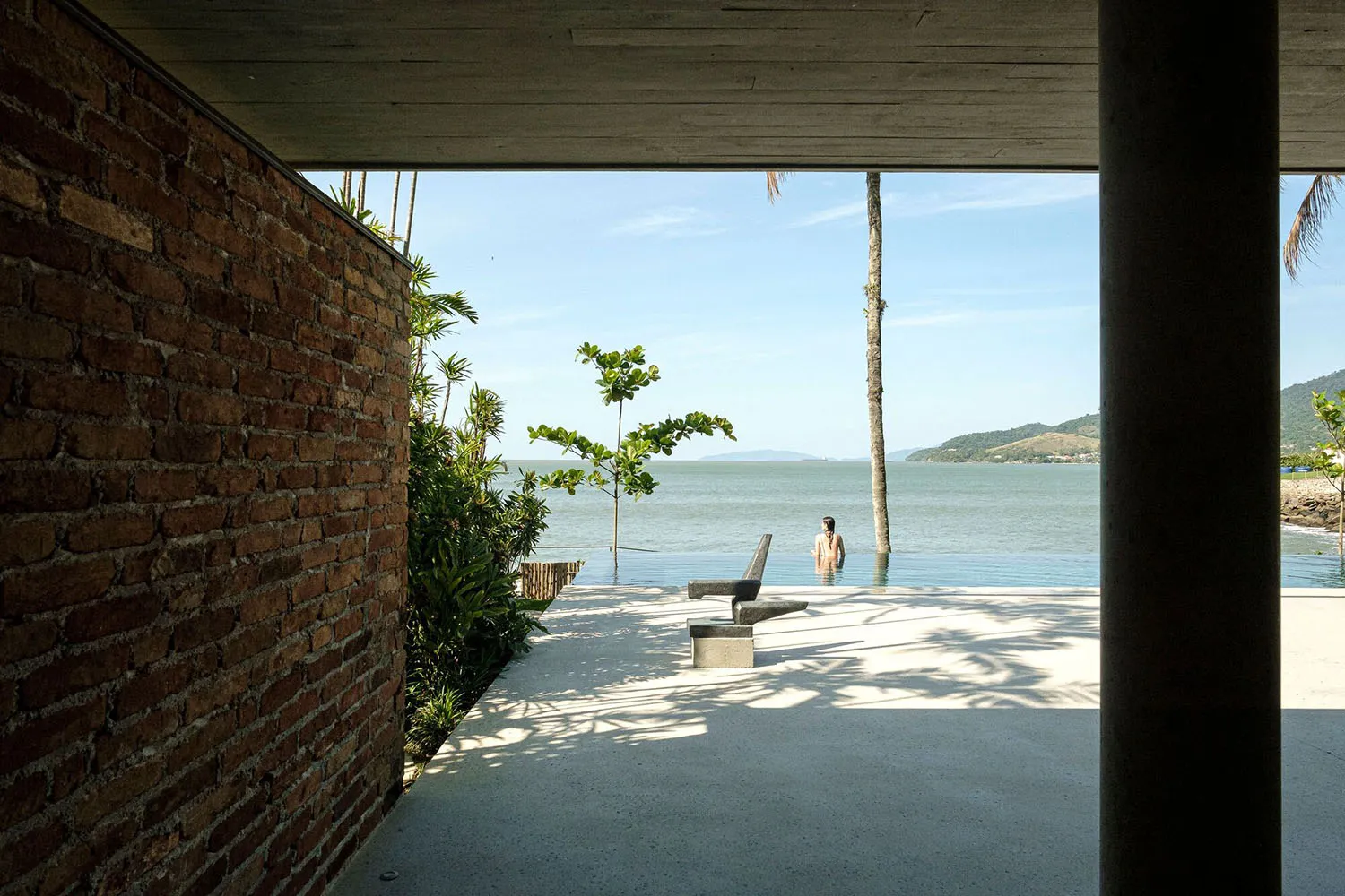 A modern poolside area with concrete elements and lush greenery.