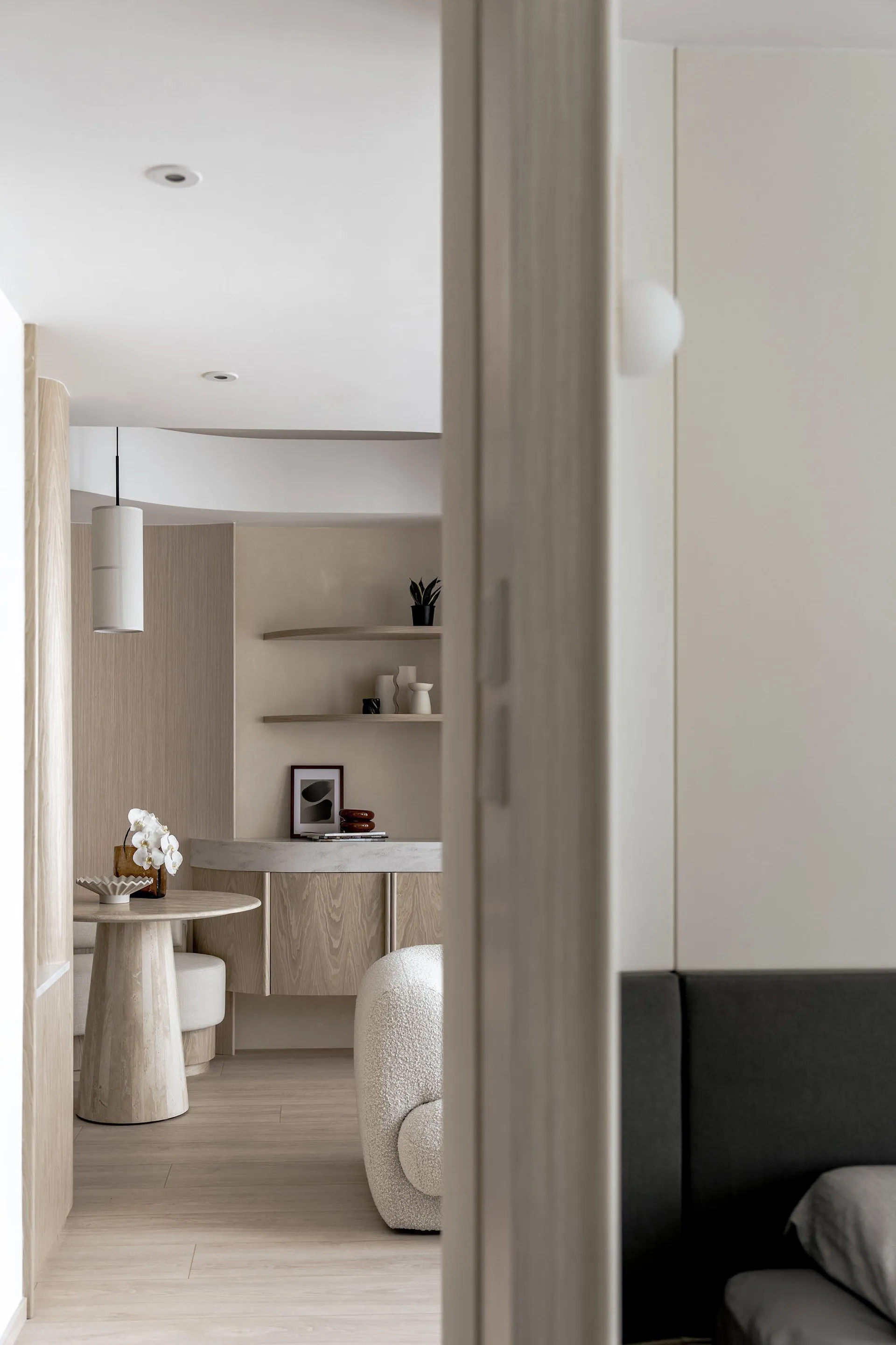 Minimalist apartment interior with wooden flooring, concrete countertops, and plush seating.