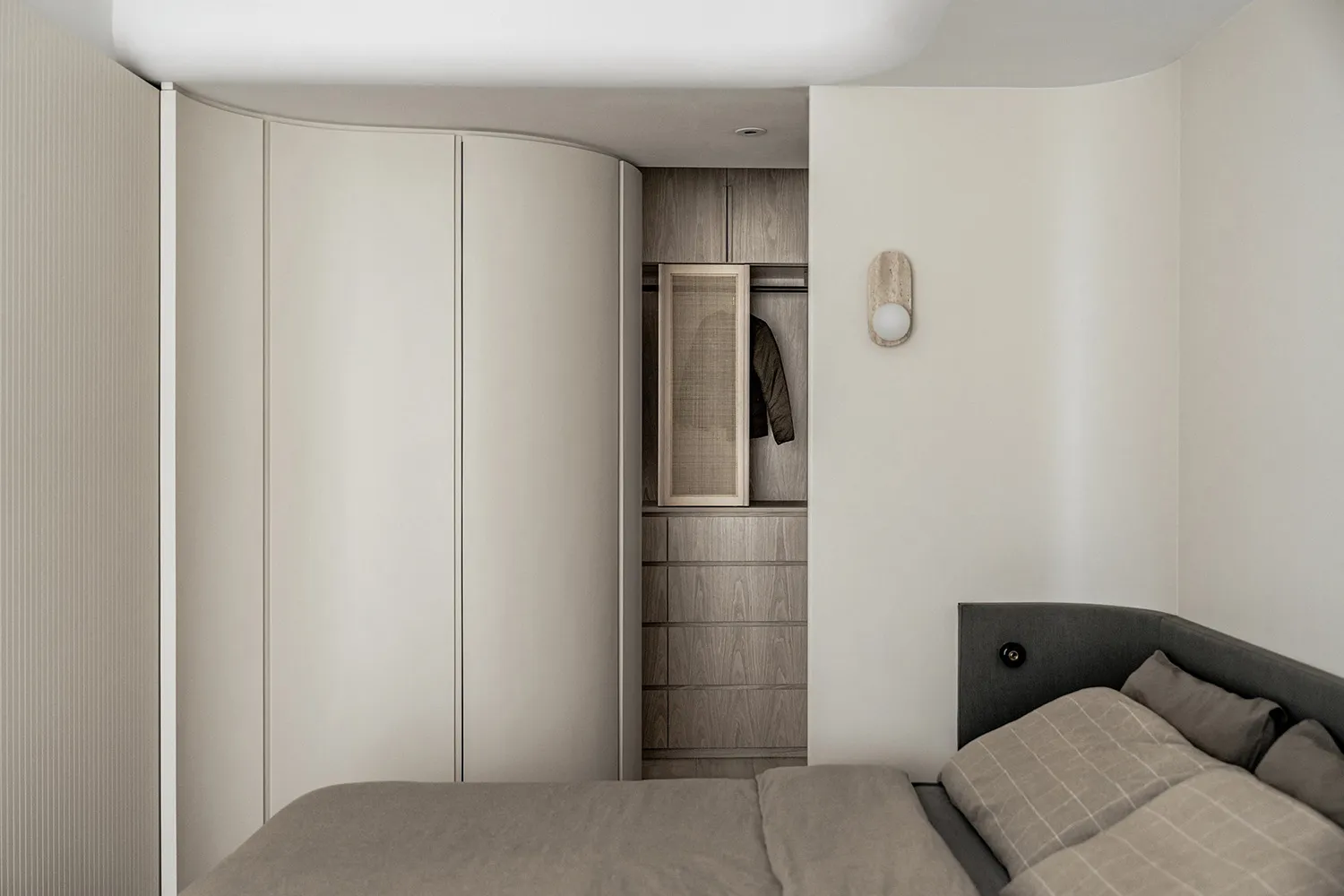 Modern, minimalist bedroom featuring neutral tones and a single bed.