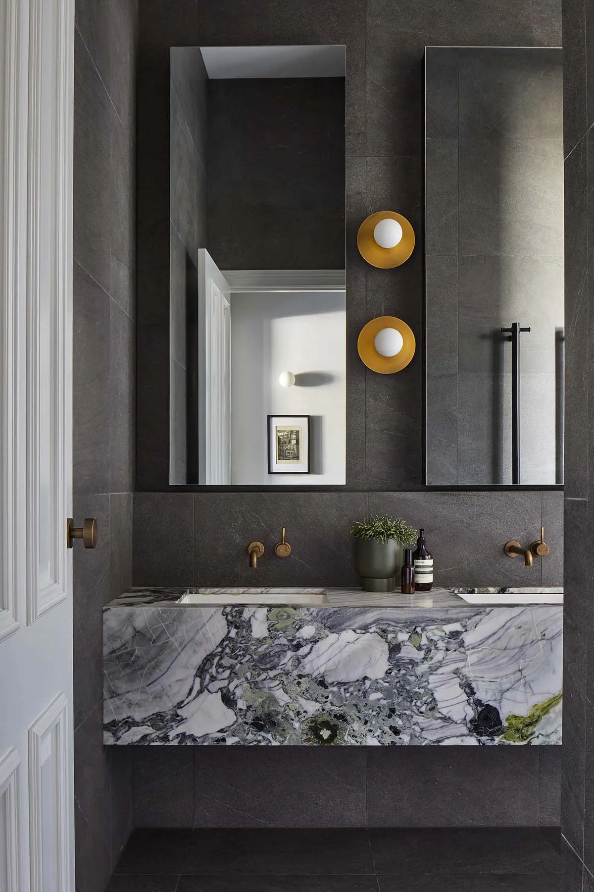 A modern bathroom with black marble countertops and dark gray tiled walls and floor.