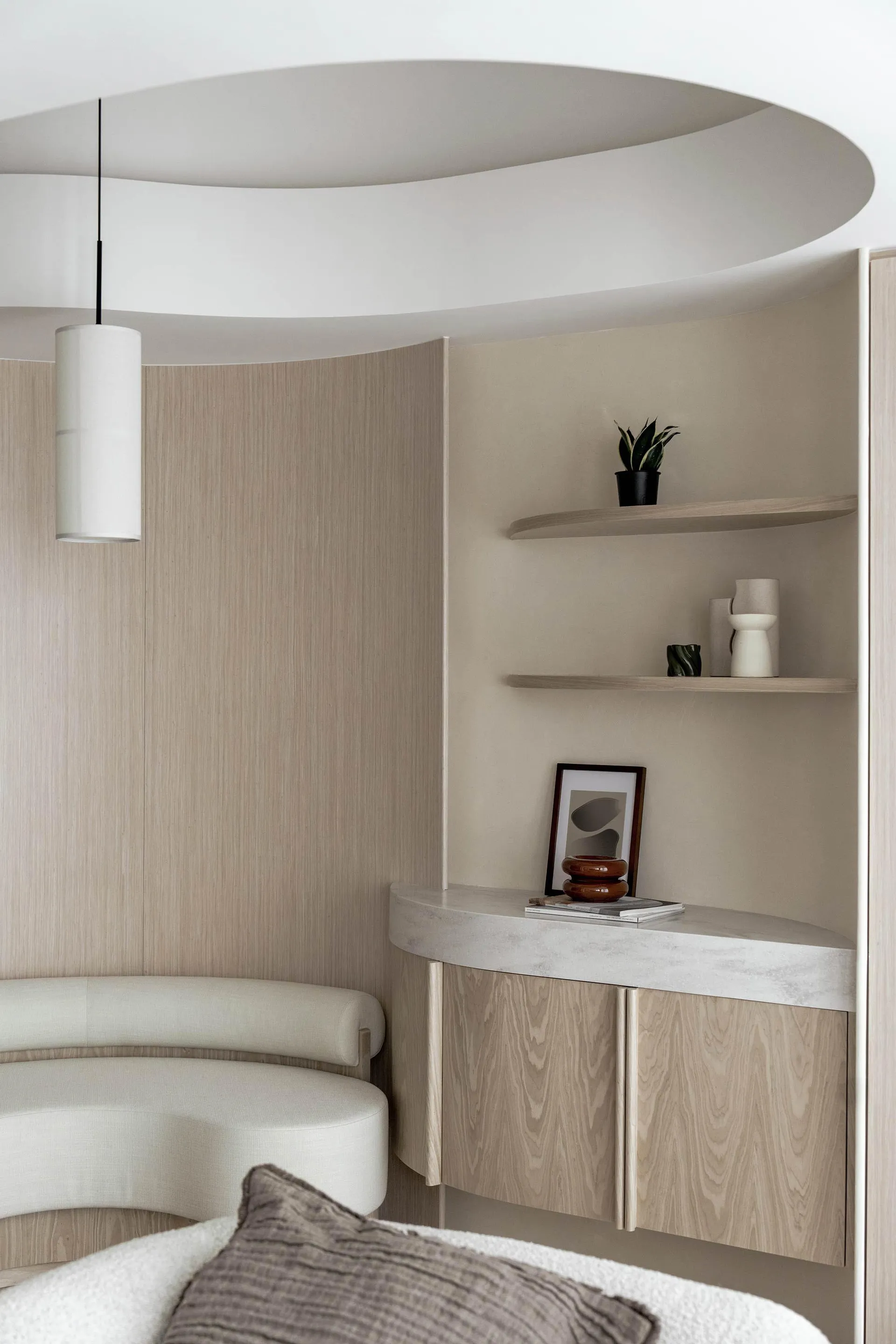 A modern bedroom featuring wood-paneled walls and a concrete shelf, with a hanging lamp and decorative objects on the shelf.