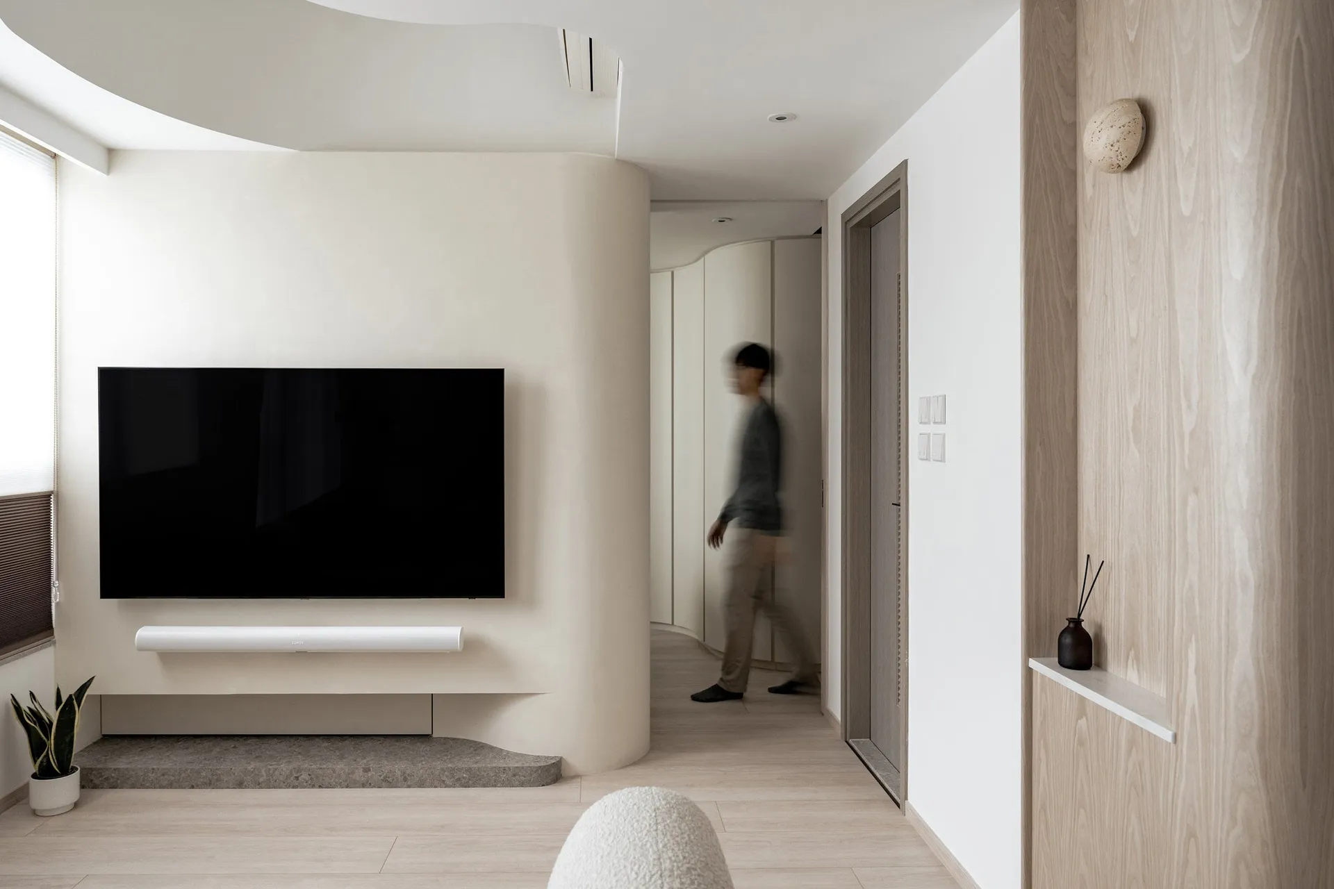Minimalist living room featuring a sleek concrete fireplace and a large flat-screen TV on a white wall.