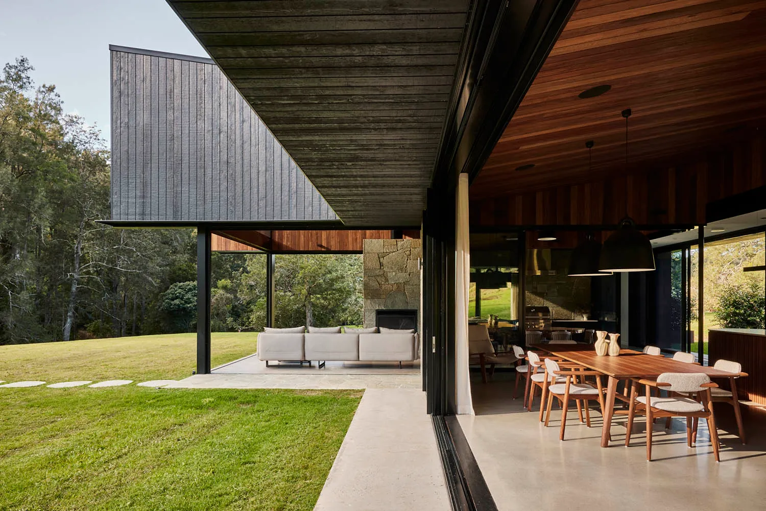 A modern residential exterior featuring wood, stone, and concrete materials.