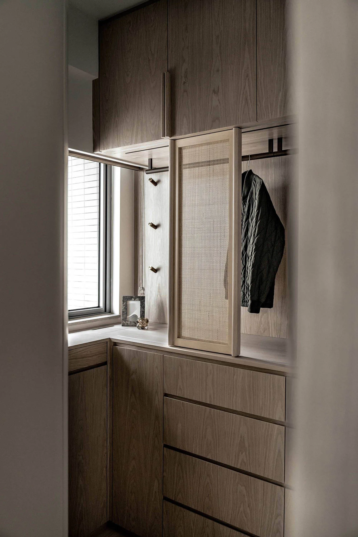 A modern wardrobe system with wooden storage units and a mesh-covered mirror.