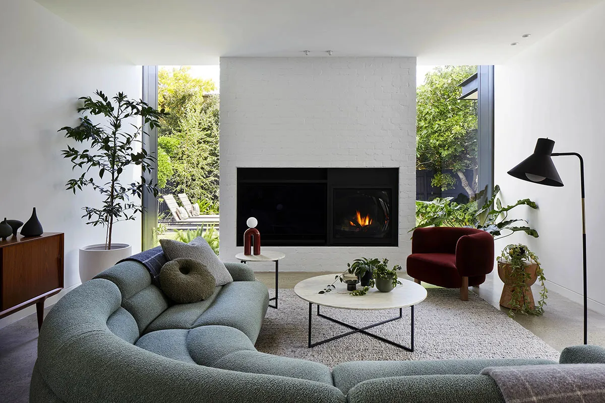 A modern living room featuring a green couch, coffee table, and fireplace.