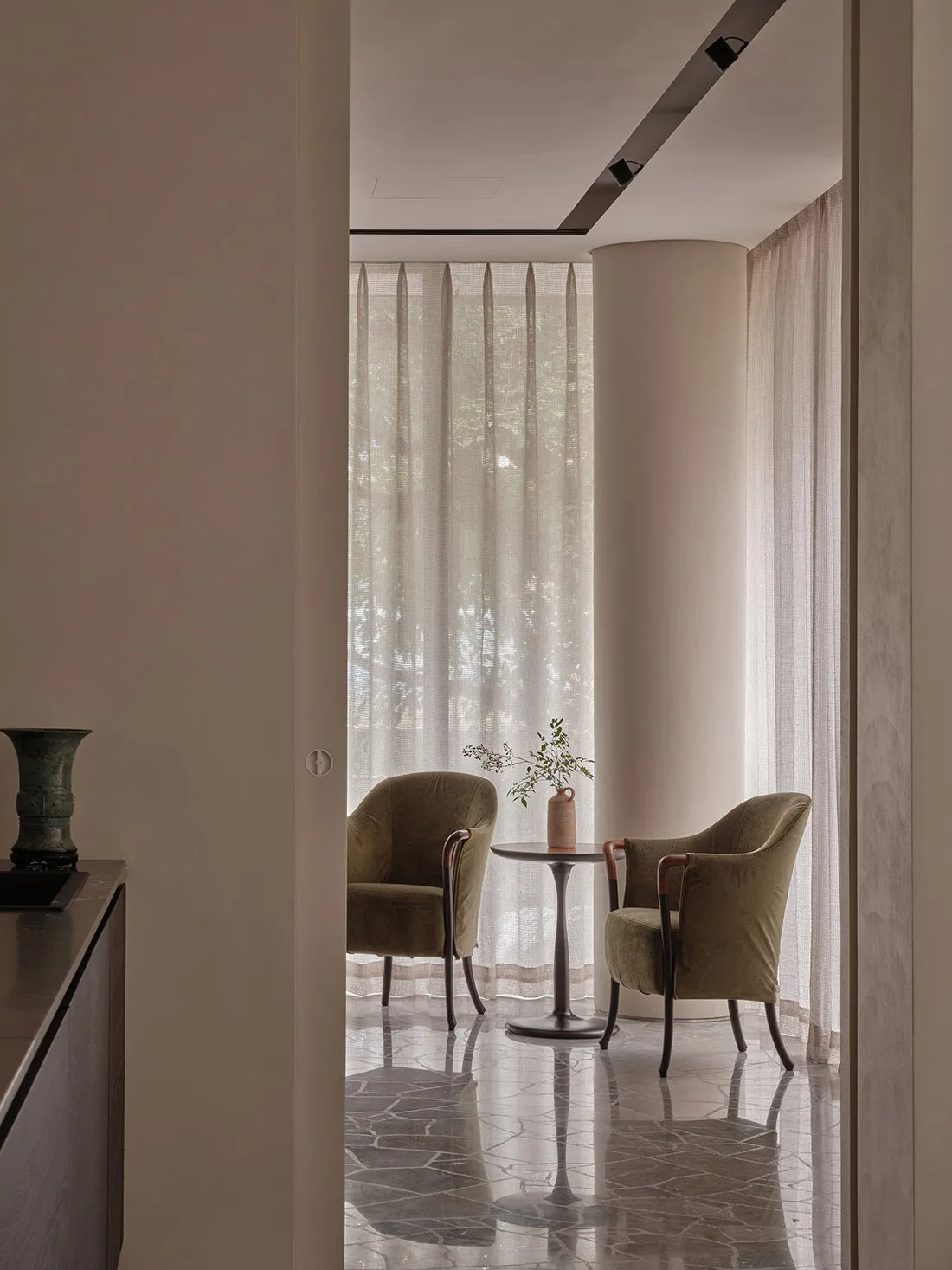 A modern living room featuring marble flooring and upholstered furniture made of fabric.