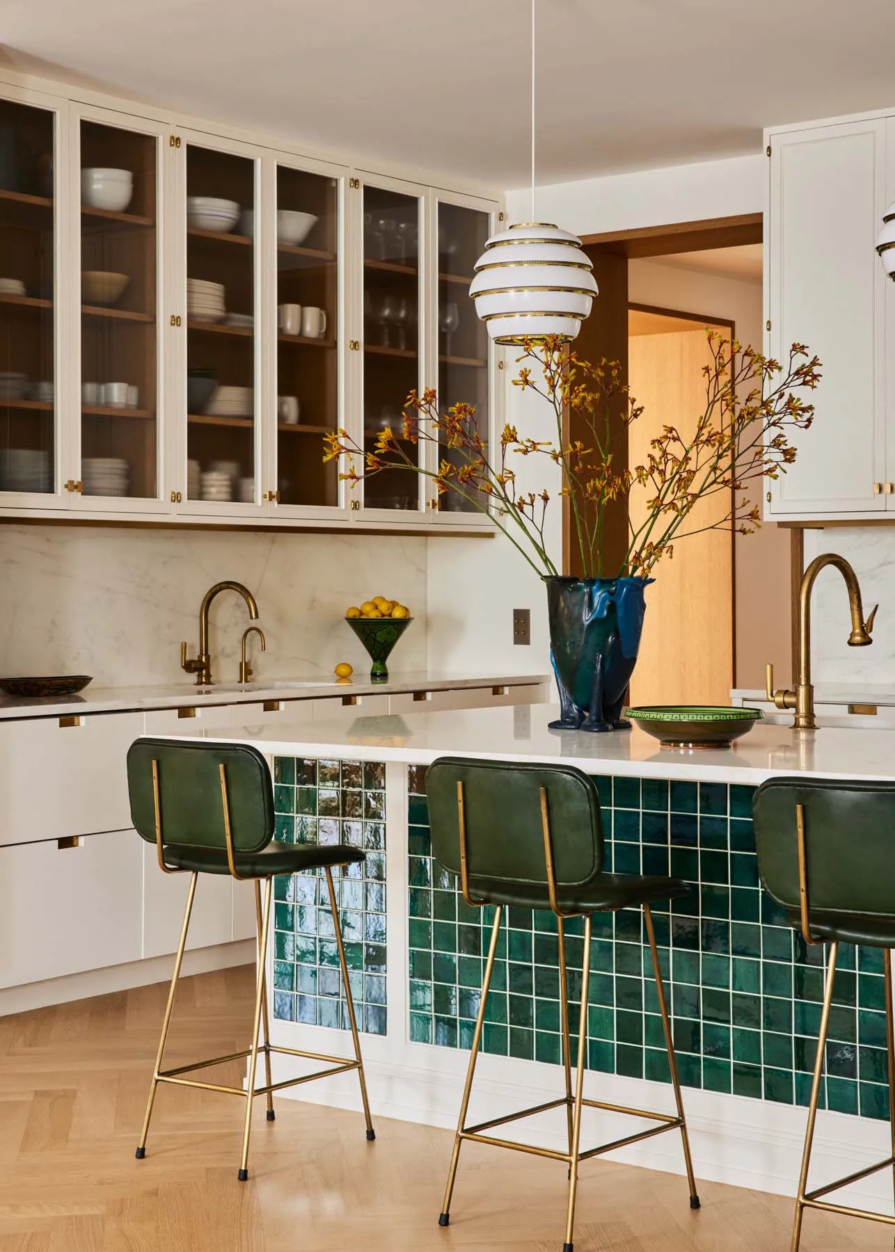 Modern, minimalist kitchen featuring green ceramic tile backsplash and marble countertops.
