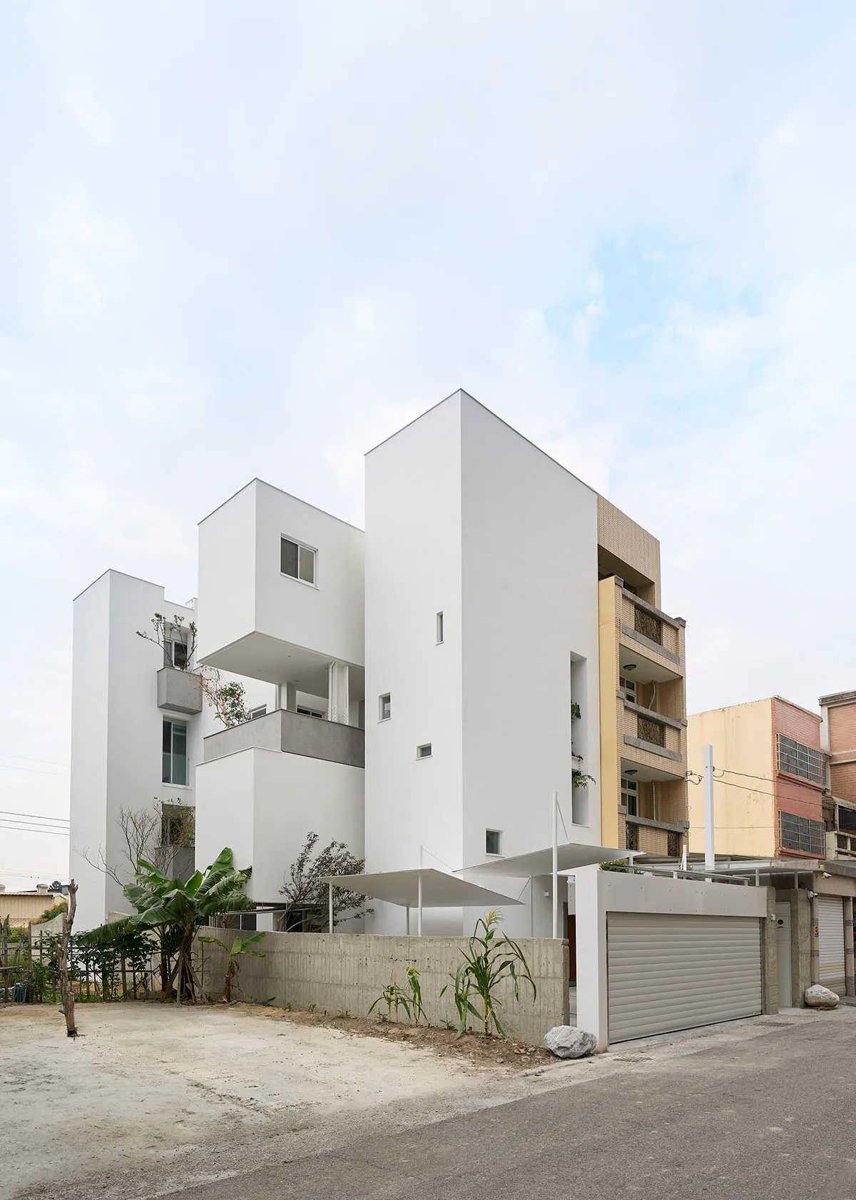 Modern, single-story house with white concrete exterior, featuring several levels and balconies.