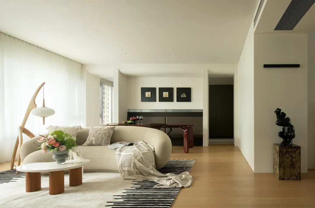 A minimalist living room with neutral-colored textiles, a modern floor lamp, and a contemporary sofa and coffee table.