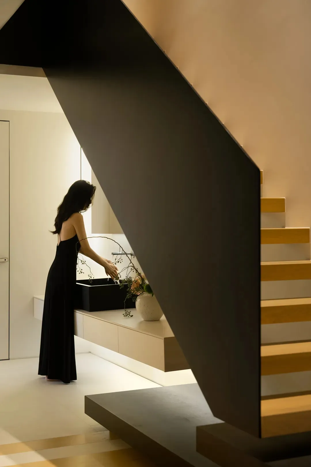 A woman washes dishes in a modern black kitchen sink with a minimalist design.
