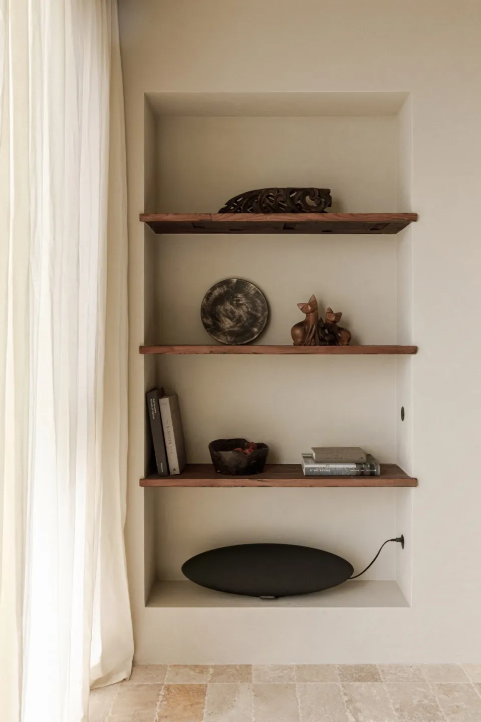 Three wooden shelves with rustic decor items such as a plate, figurines, and books.