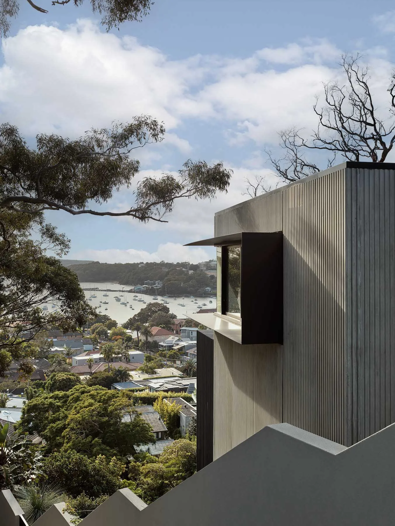 A modern building with a metallic exterior overlooking a bay with boats.