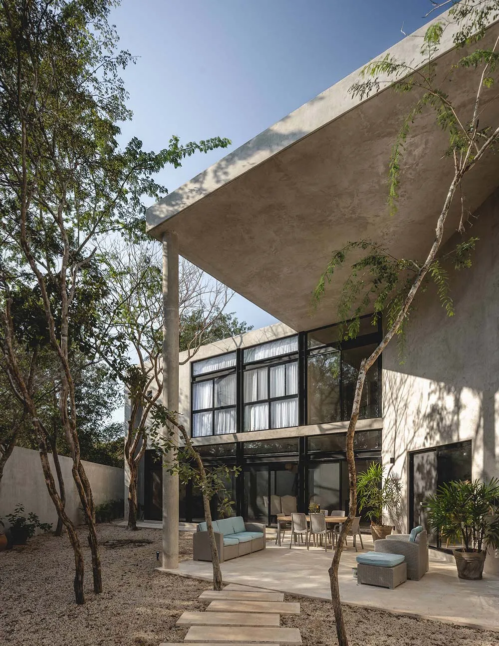 Concrete exterior of a modern building with large windows and a patio area.
