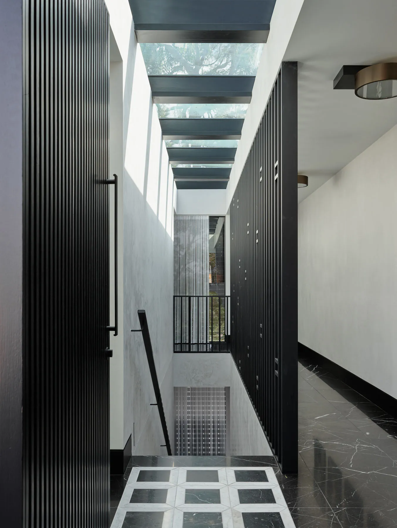 A modern interior design featuring glass ceiling, black columns, and marble flooring.