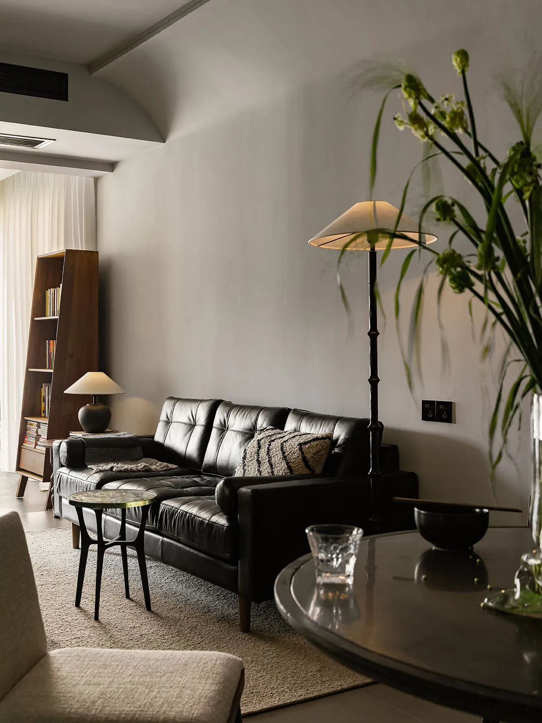 Modern minimalist living room featuring a sleek black leather sofa and a glass side table
