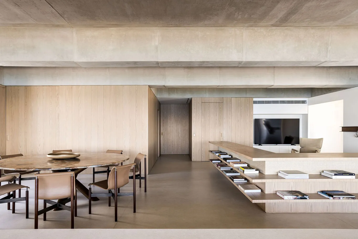 A minimalist living room with a concrete ceiling, wooden walls, and a marble table.
