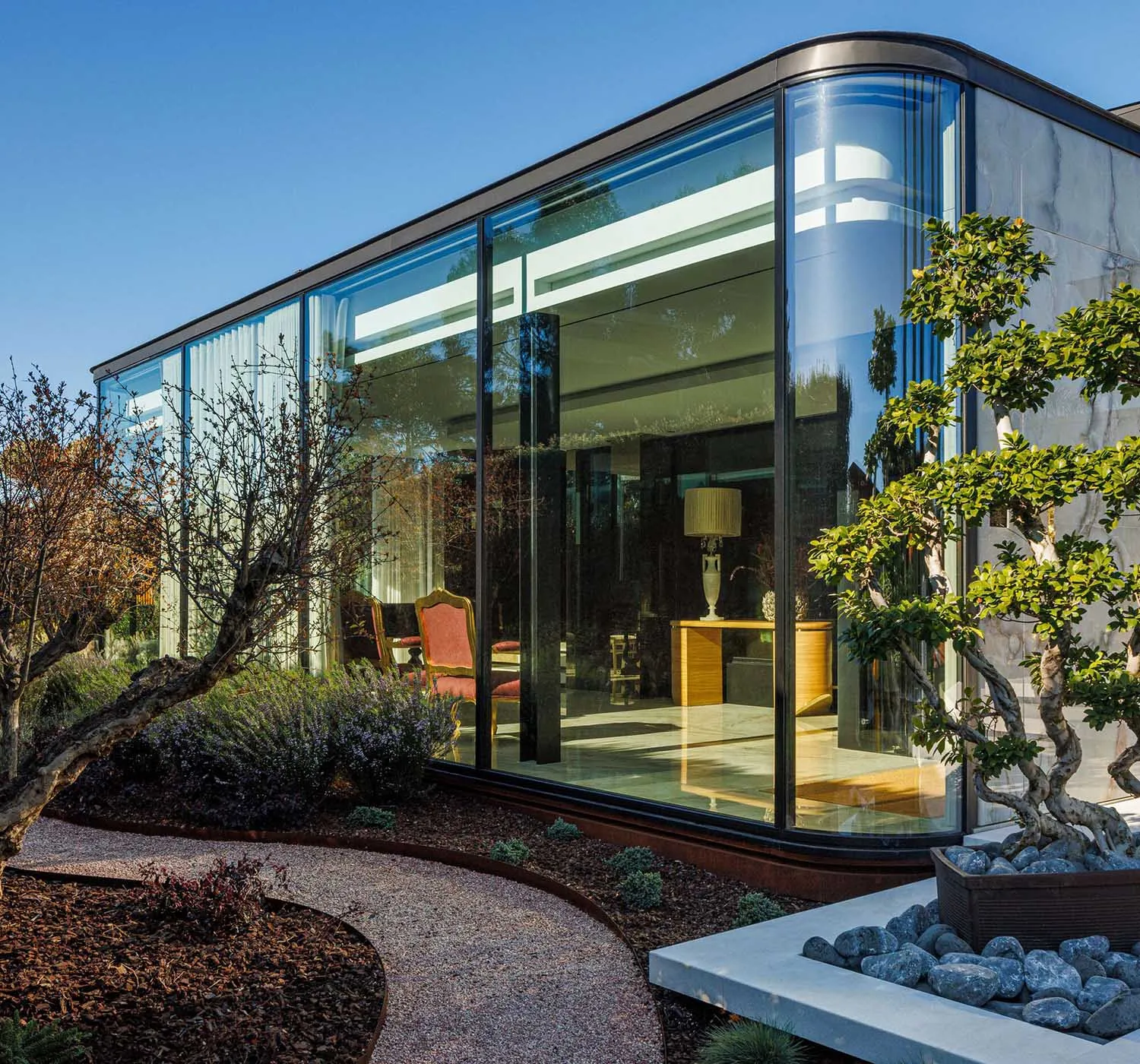 Modern glass building exterior with curved windows and landscaping.