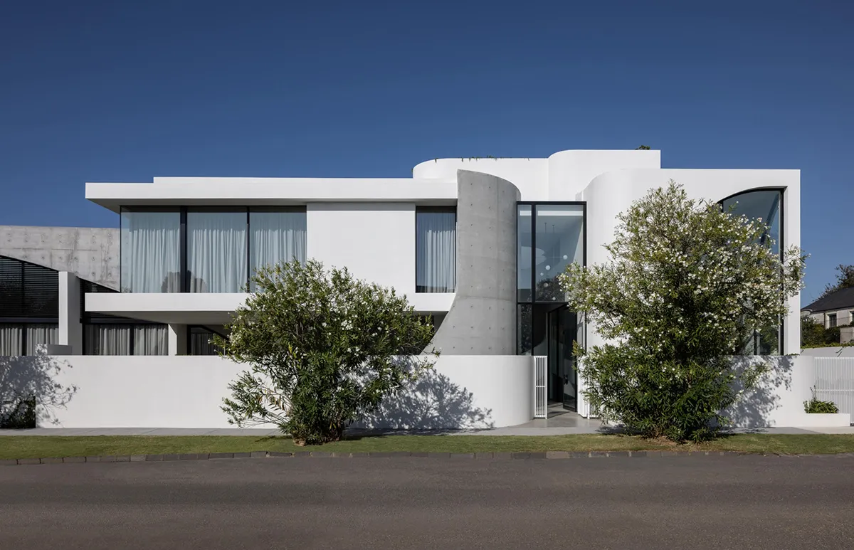 A modern house with a white exterior, concrete elements, and large windows.