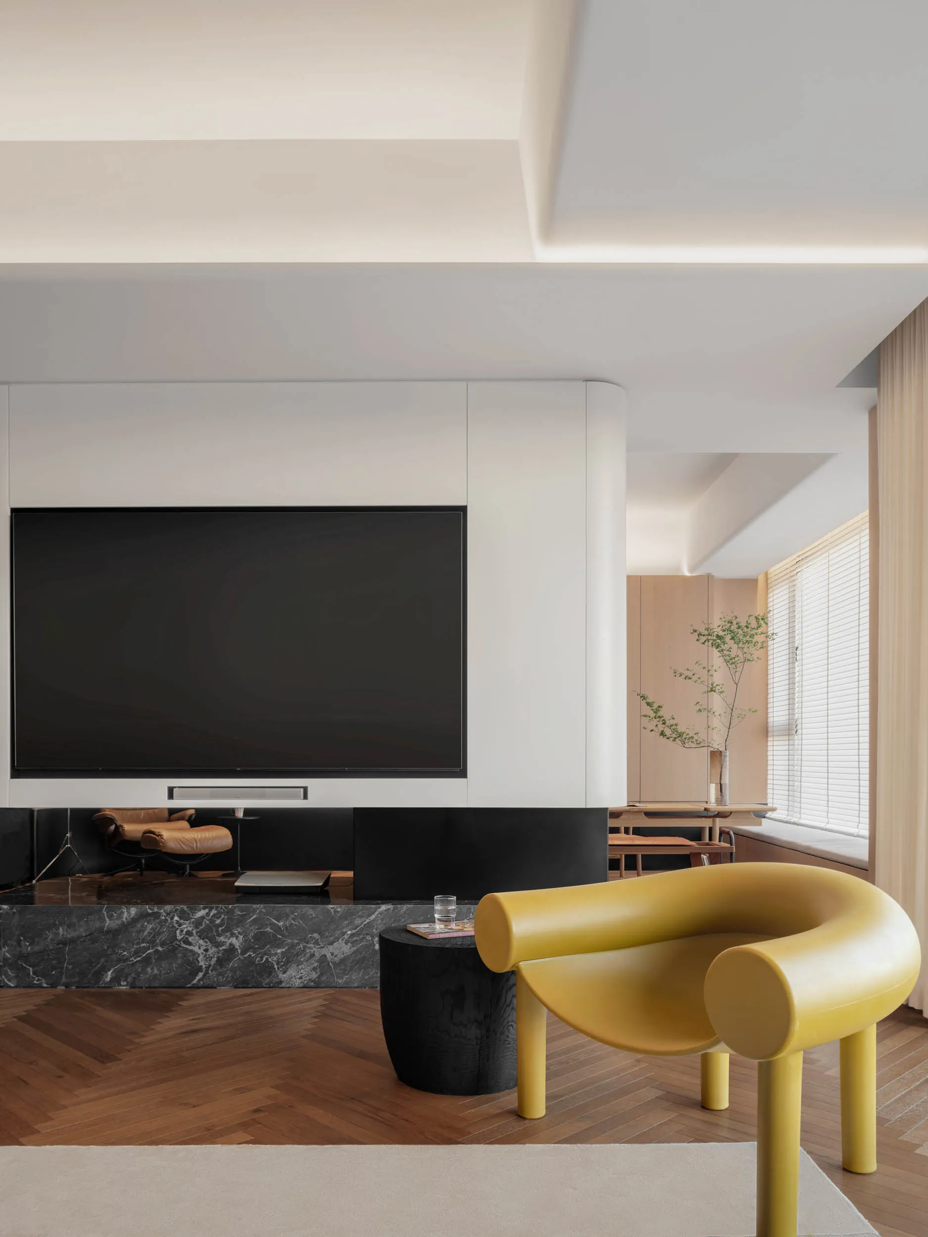 A modern living room featuring a large flat-screen TV, contemporary furniture, and a marble floor.