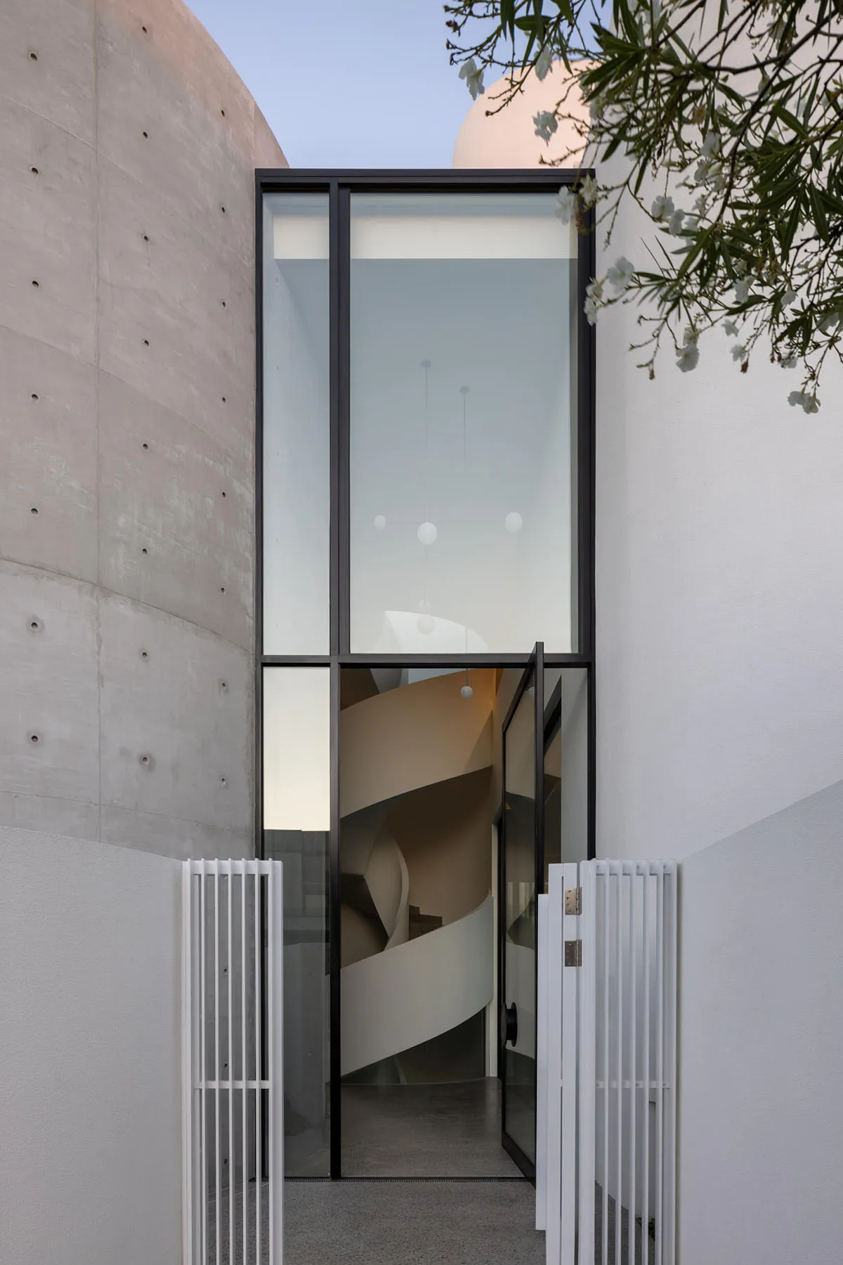 A modern residential entryway featuring glass and concrete materials.