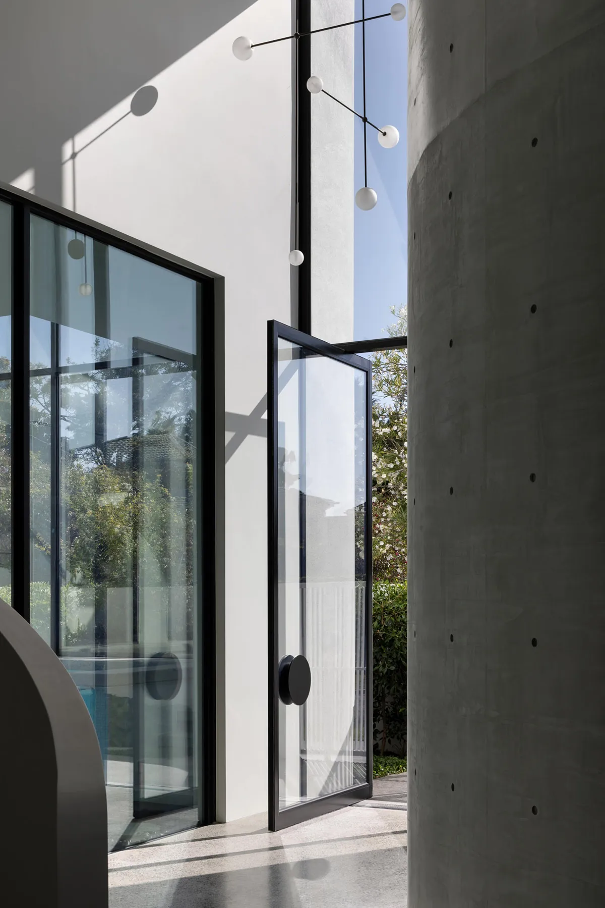 Modern entrance featuring transparent glass walls, sleek concrete columns, and black structural elements.