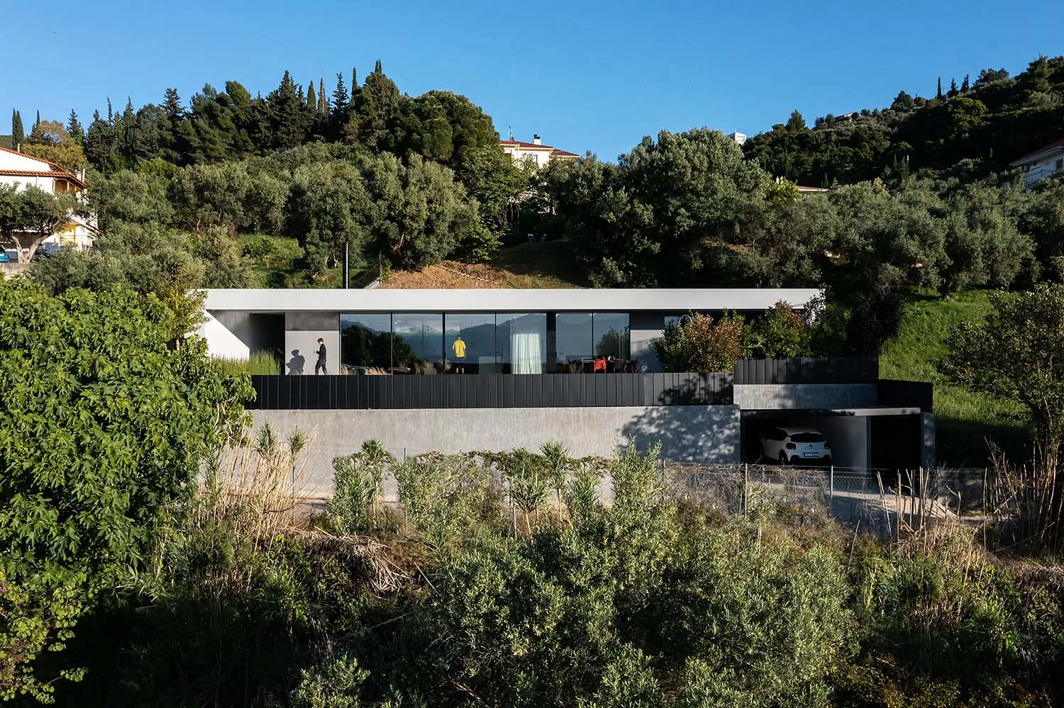 A modern house with a minimalist design, featuring a combination of concrete and glass materials.
