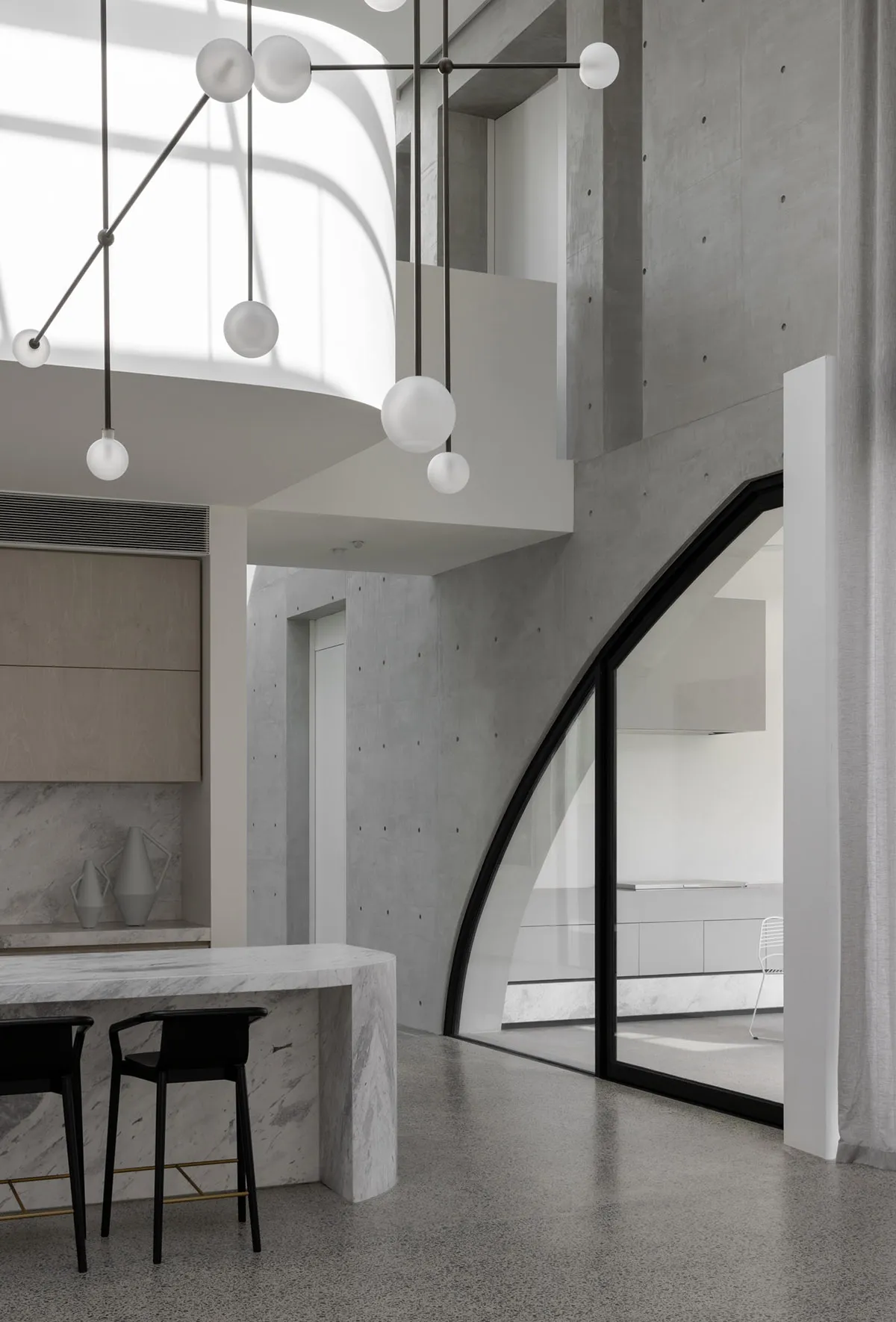 Modern kitchen with concrete walls, marble countertops, and minimalist design.