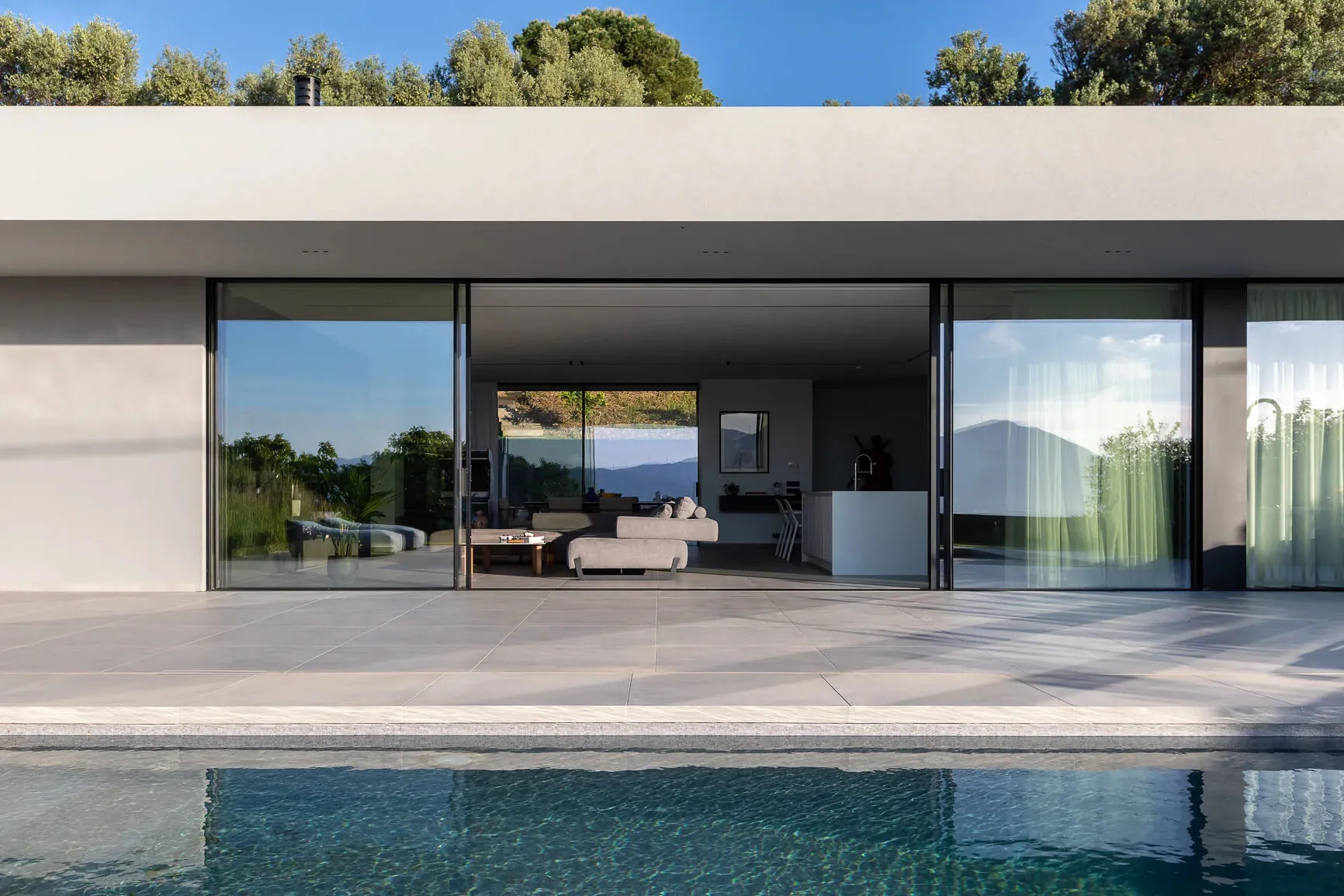 Modern minimalist residential space with large glass walls and a clean, contemporary design.