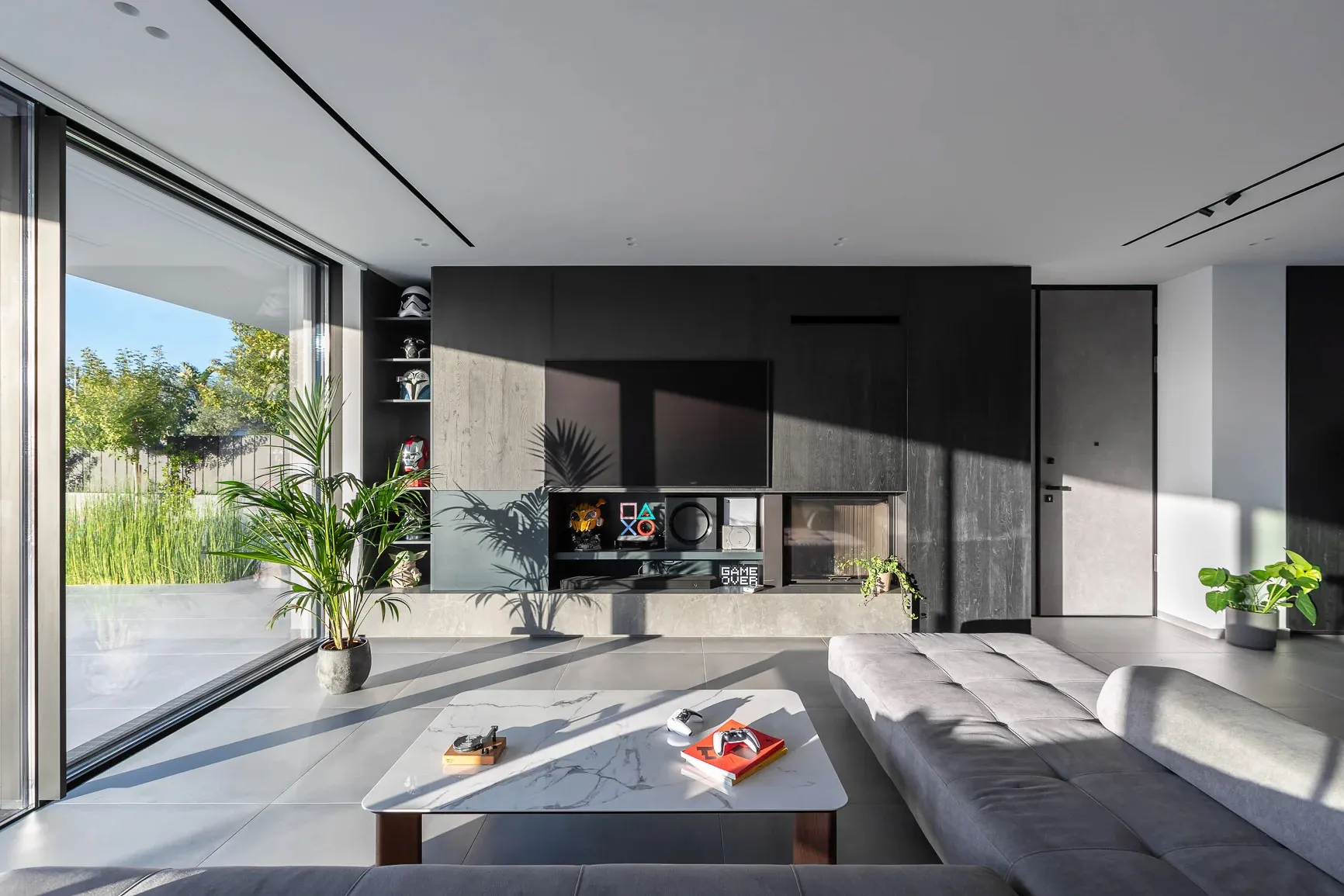 A modern minimalist living room featuring a concrete floor, glass wall, and wooden furniture.
