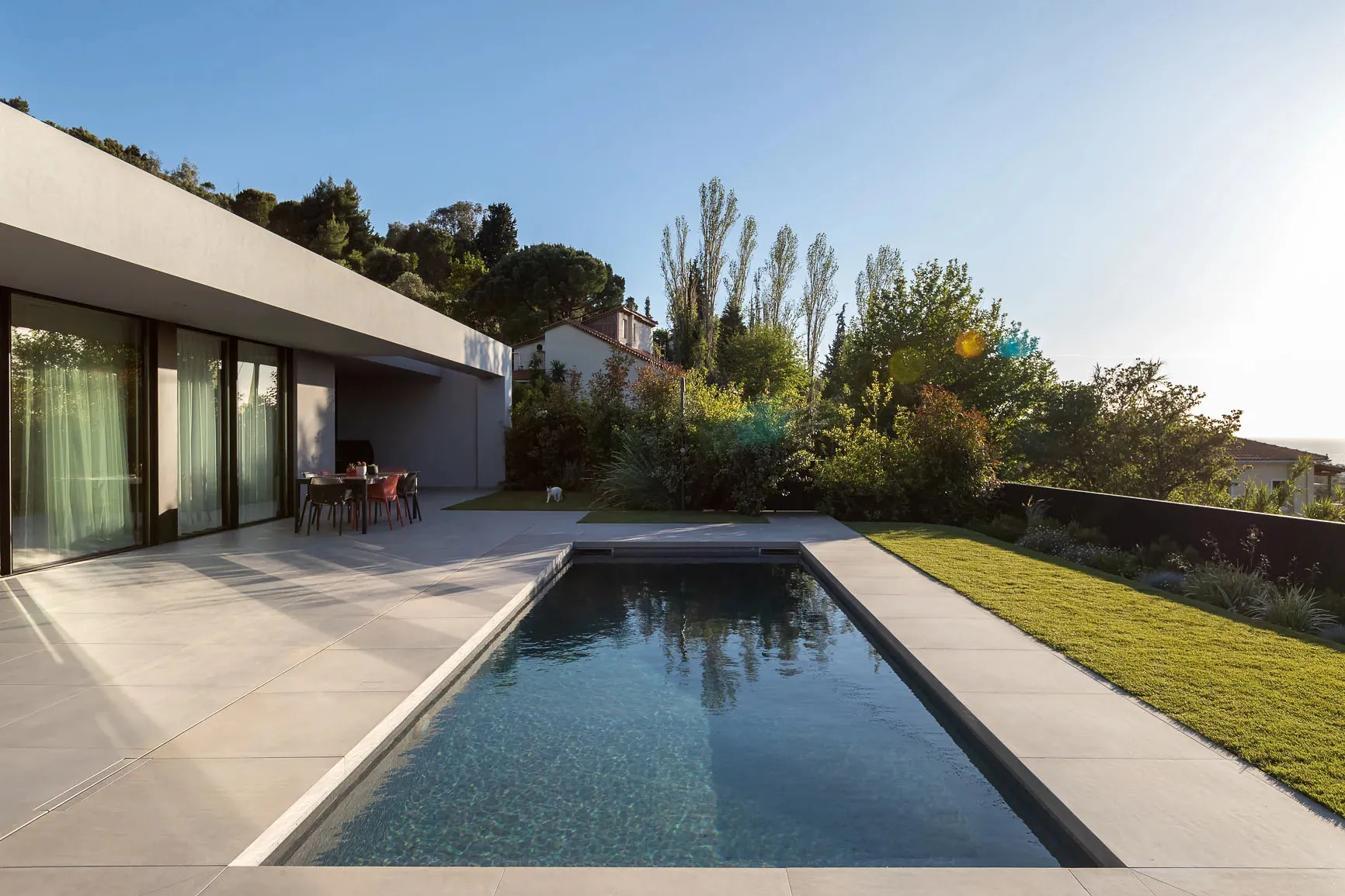 A modern residential home with a concrete pocket pool surrounded by a well-manicured garden.