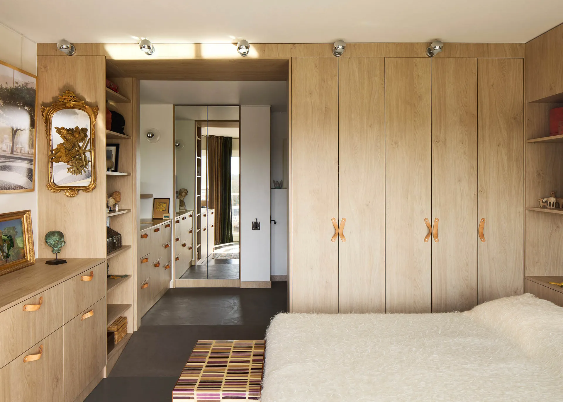 A minimalist bedroom featuring wooden storage cabinets, a plush bed, and a modern design.