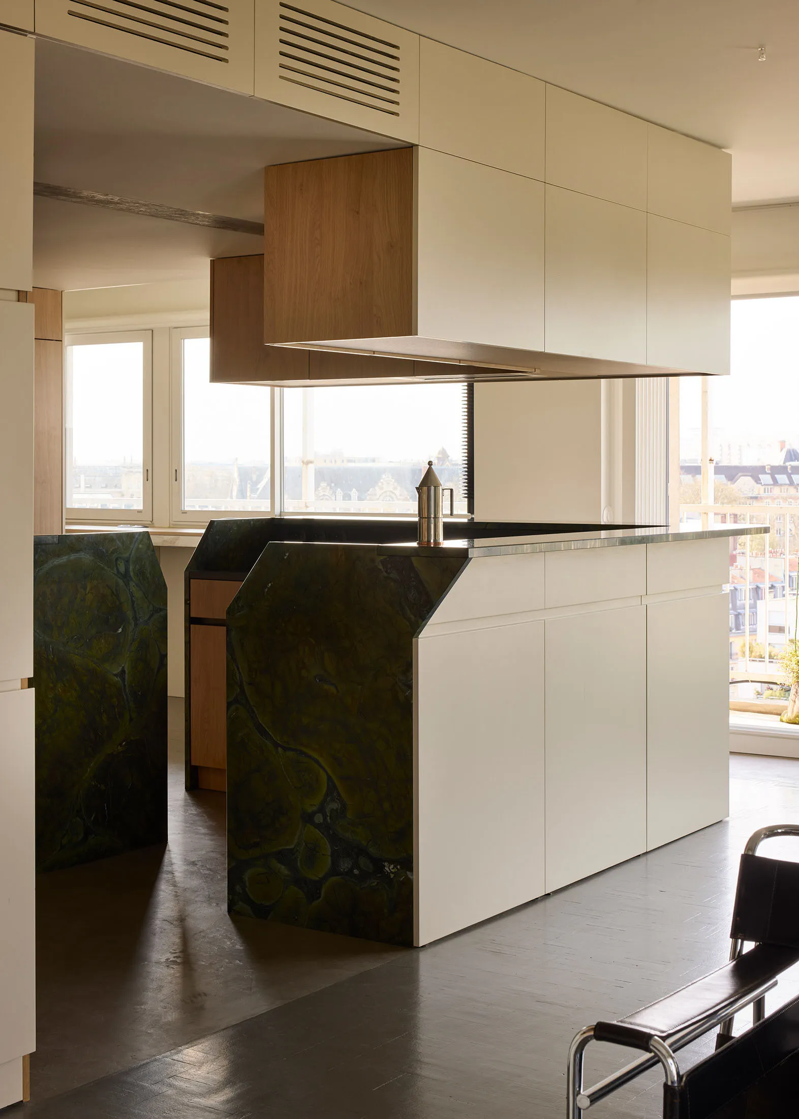 Modern minimalist kitchen featuring white cabinets, a marble island, and a concrete pendant light.