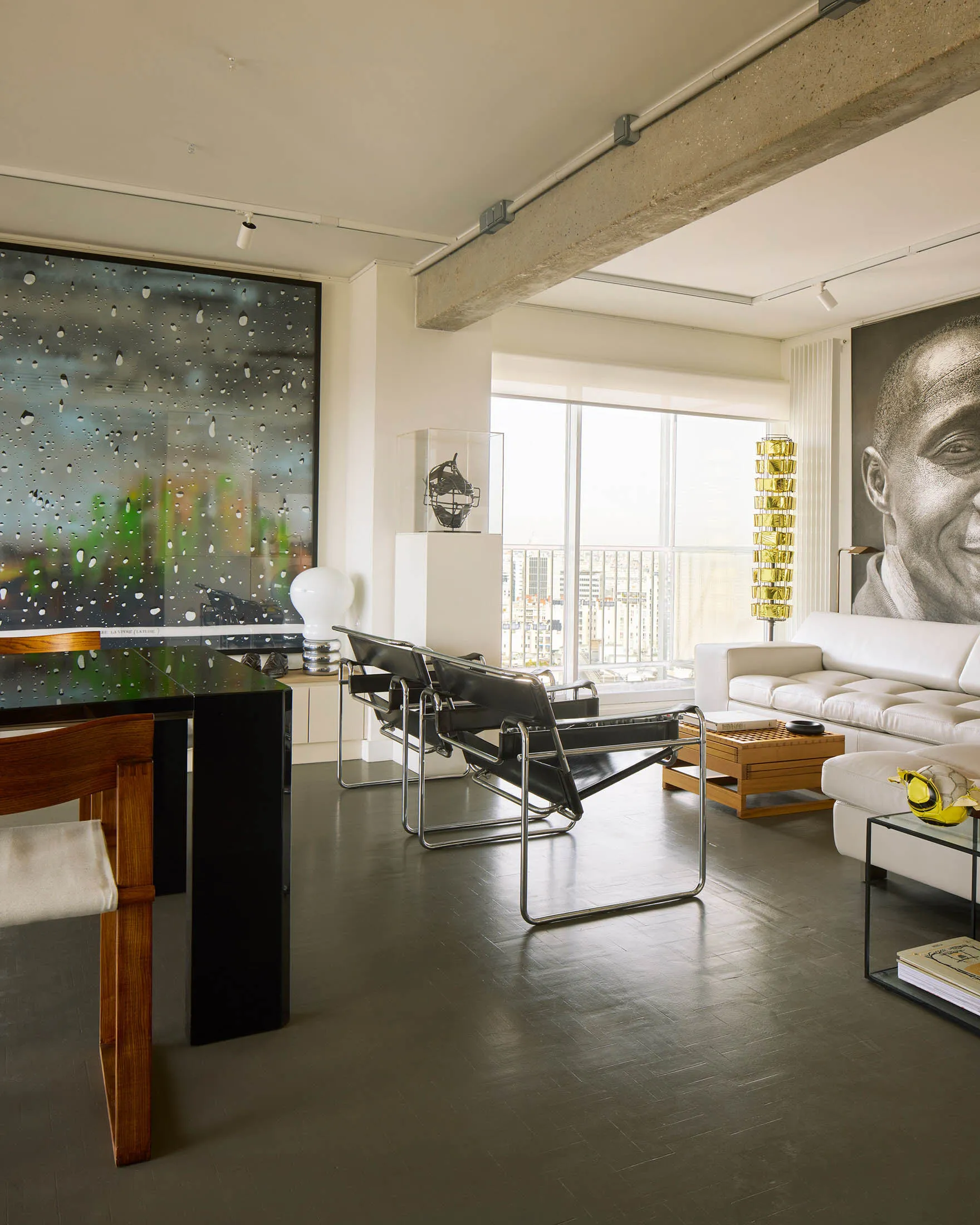 A modern living room featuring concrete walls, metal chairs, and wooden furniture.
