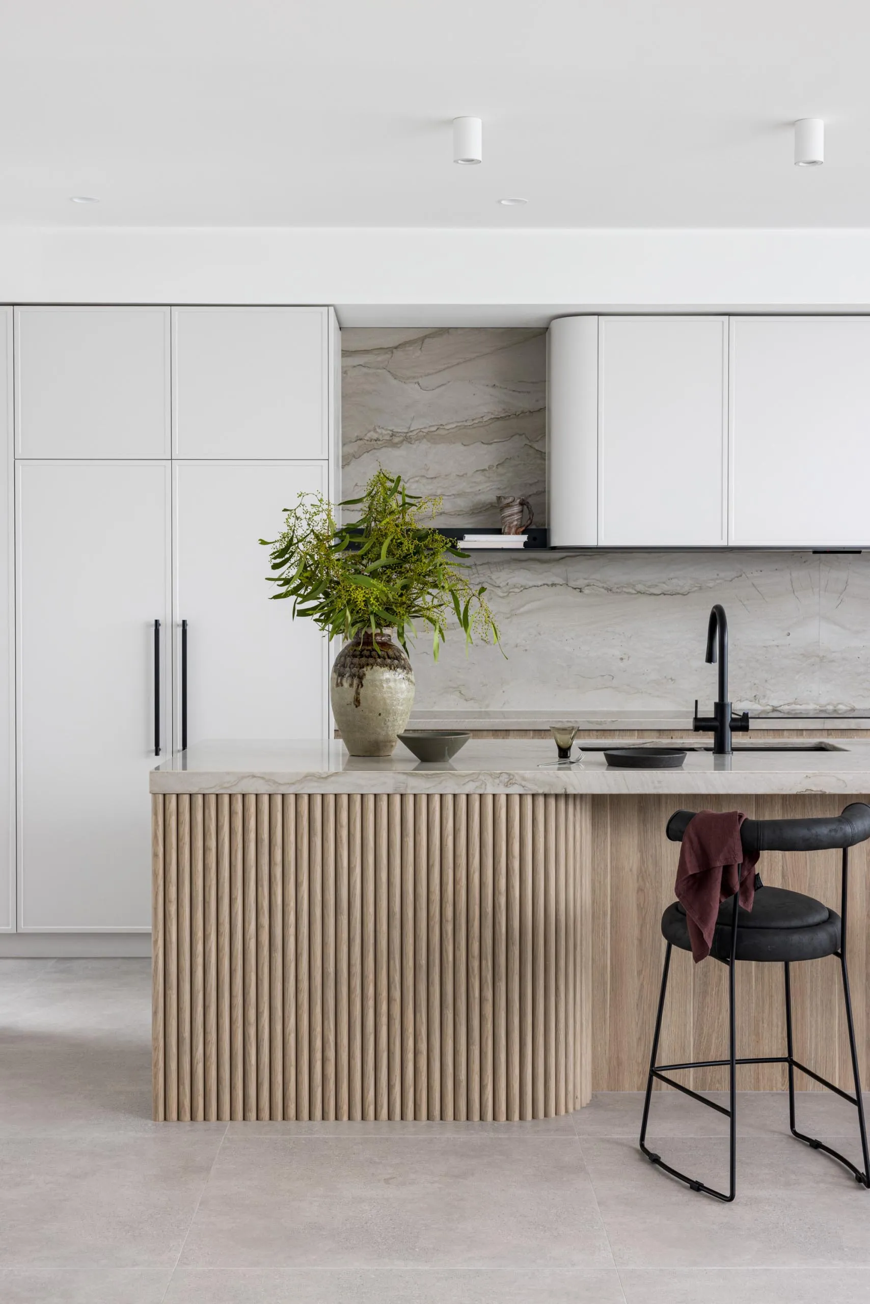 Modern minimalist kitchen featuring wood paneling and marble countertops