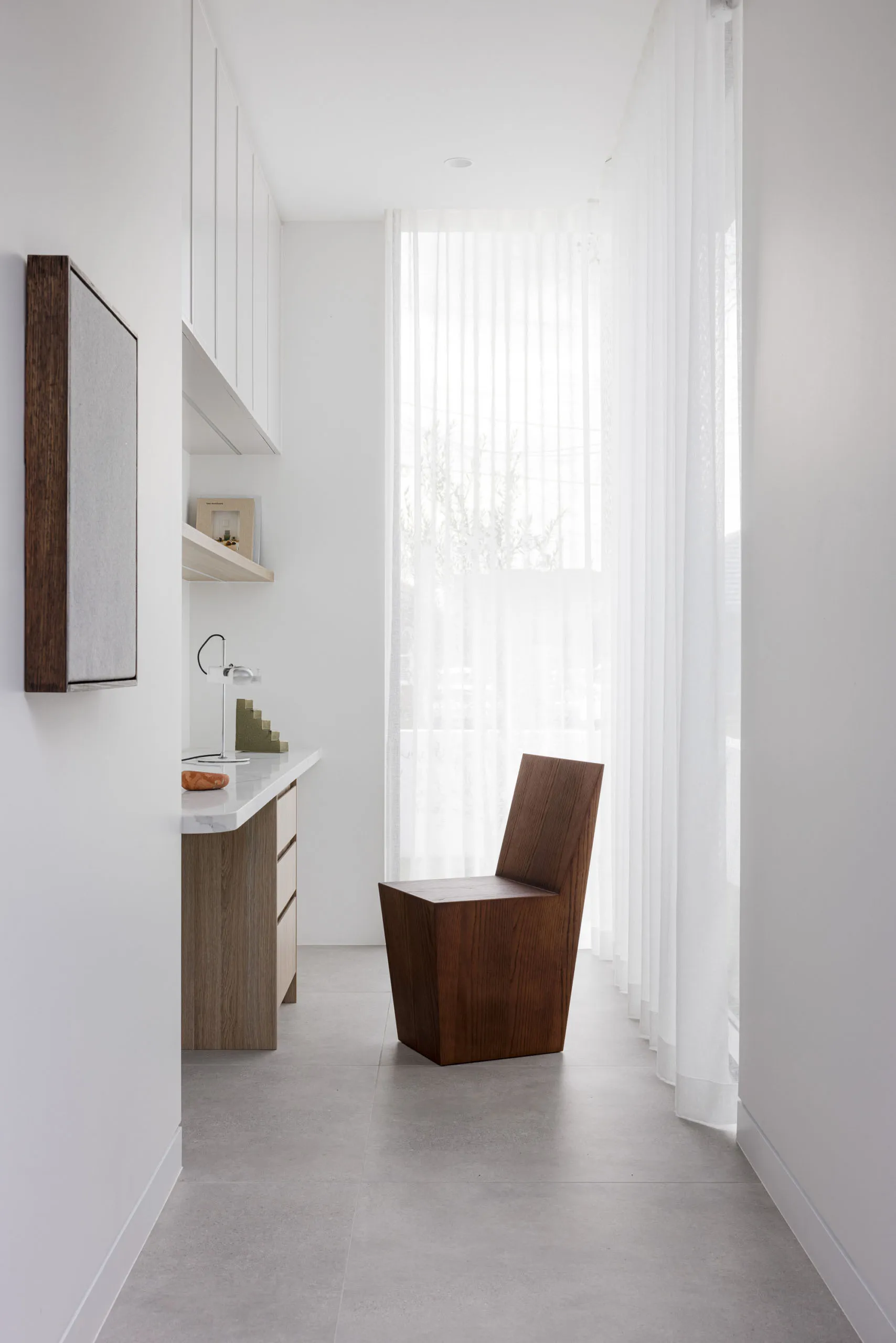Modern residential interior featuring a wooden chair, a glass wall, and concrete flooring.