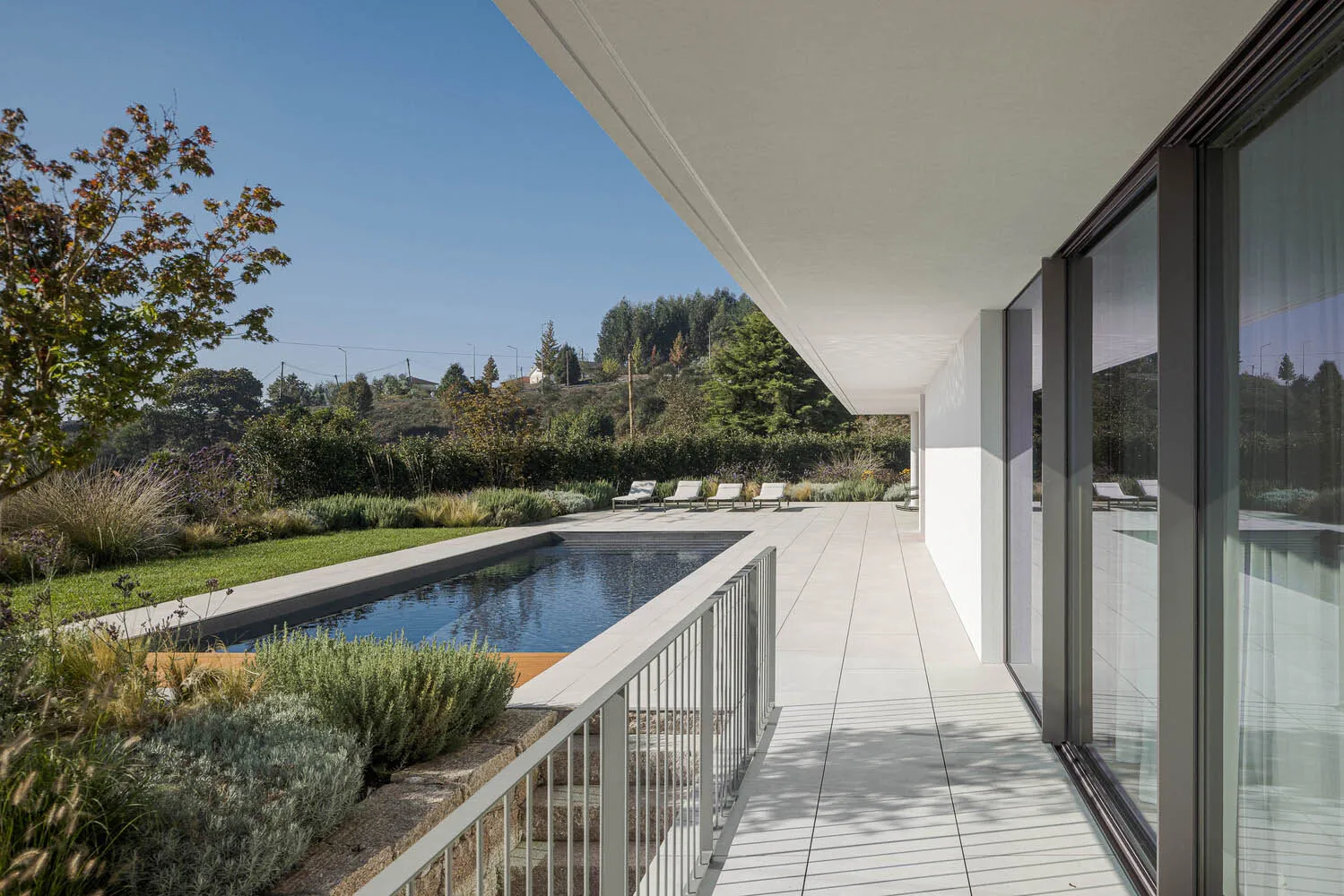 Modern minimalist residential exterior with concrete, glass, and wood materials.