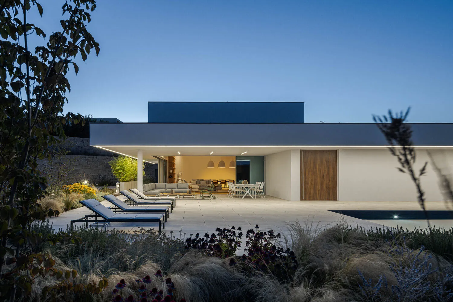 A modern residential exterior featuring concrete, glass, and metal materials.