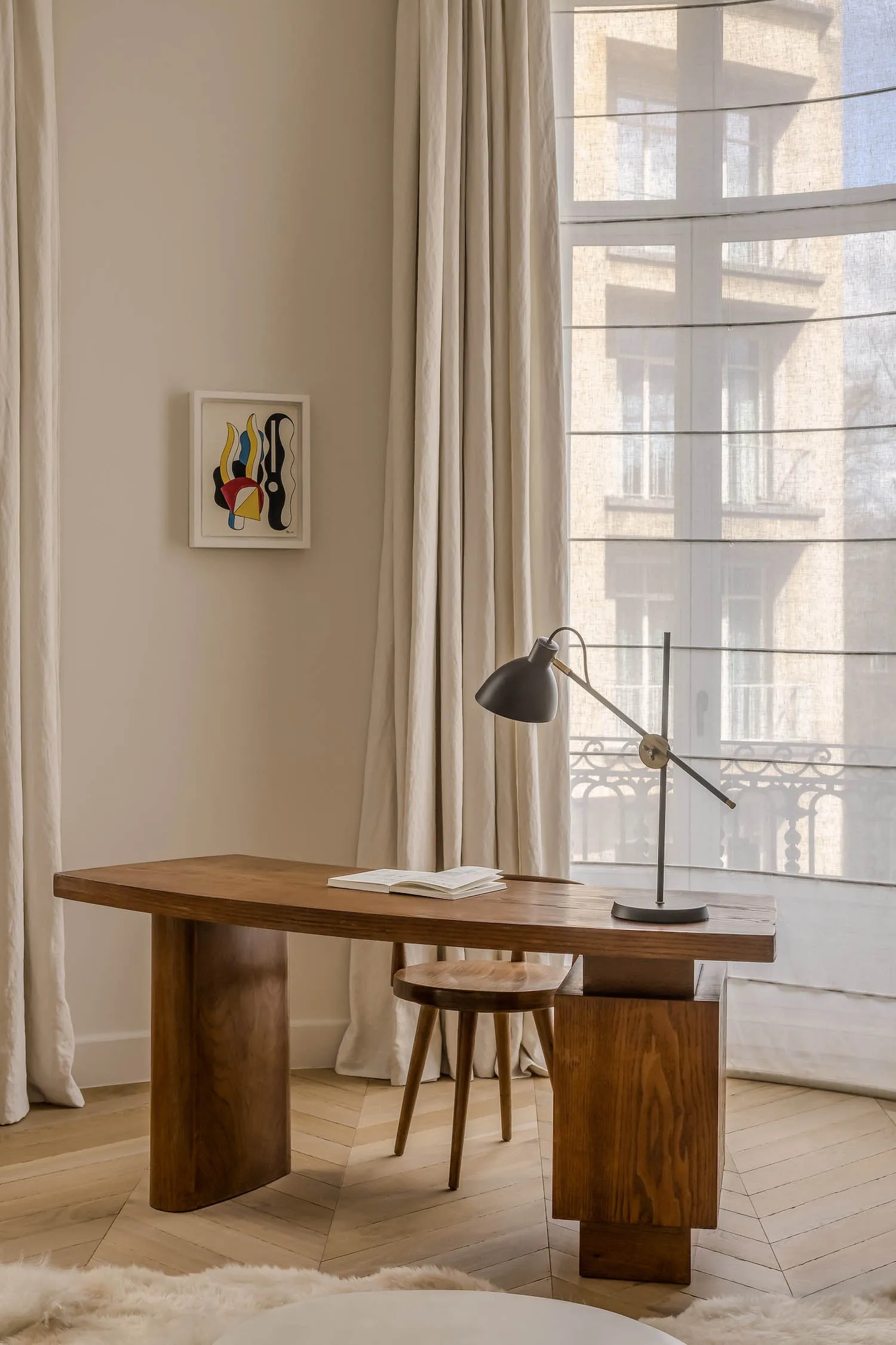 A modern study area featuring a wooden table, a simple stool, and a contemporary lamp.