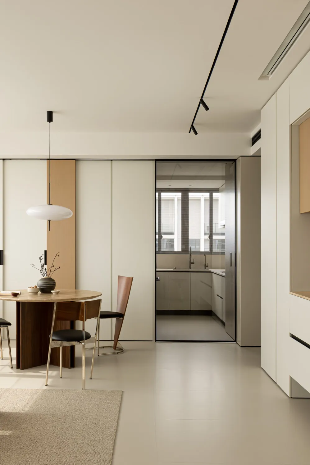 A modern minimalist kitchen with white laminate cabinets and a white pendant light fixture.