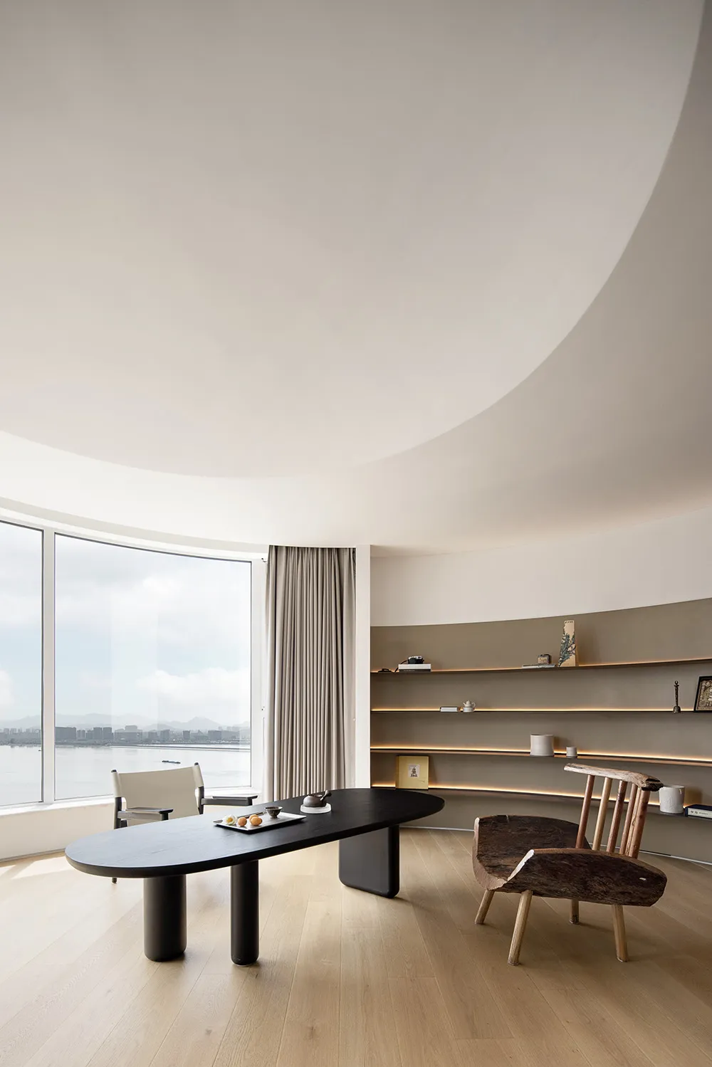 Modern living room featuring a sleek wooden table and ceramic accents on a white wall with built-in lighting.