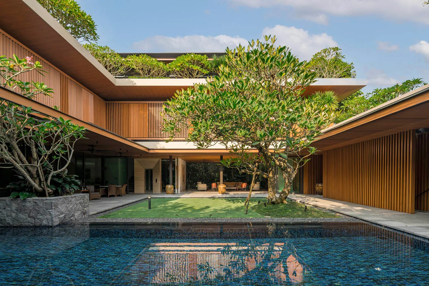 Contemporary residential house with wooden exterior and lush greenery.