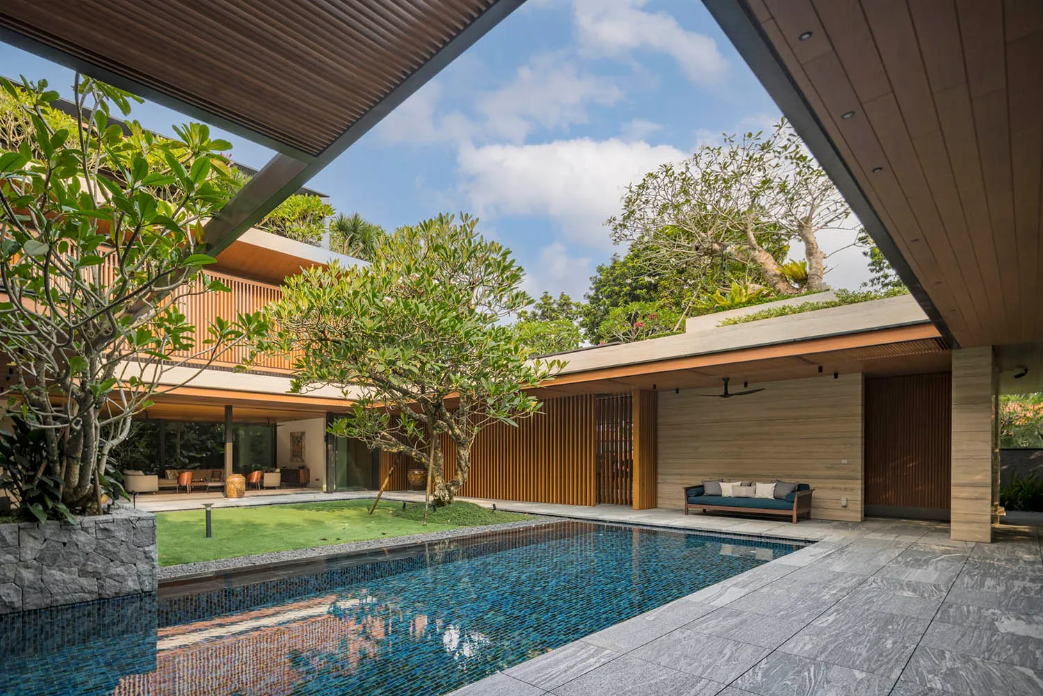 Modern residential interior featuring wooden elements, concrete flooring, and a green roof with a landscaped yard.