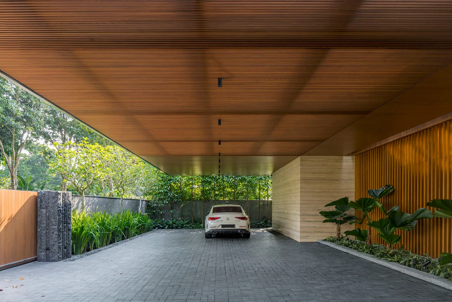 A modern car park interior featuring wooden ceiling, concrete floor, and greenery.