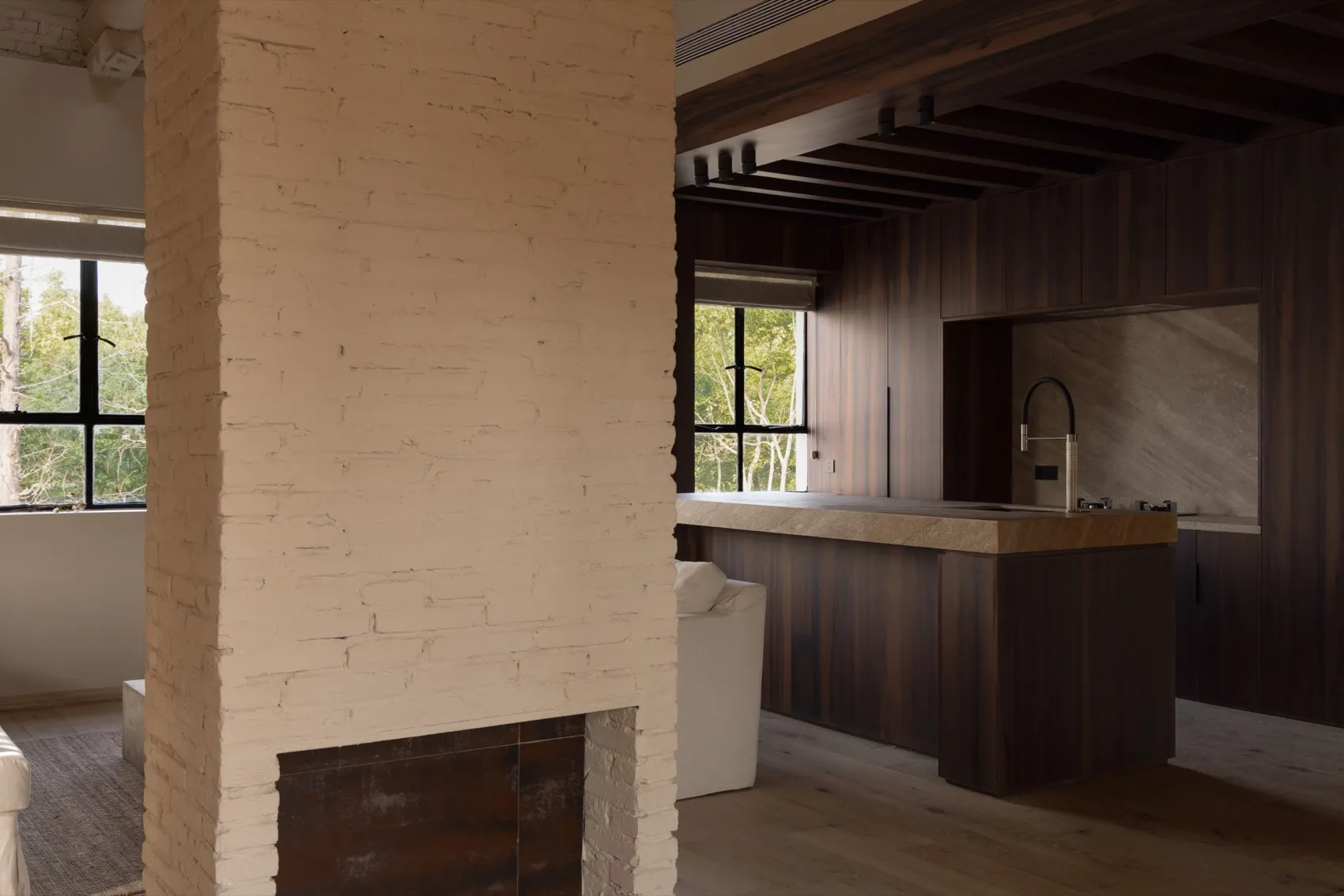 Modern, minimalist kitchen with wooden cabinets and a brick wall.