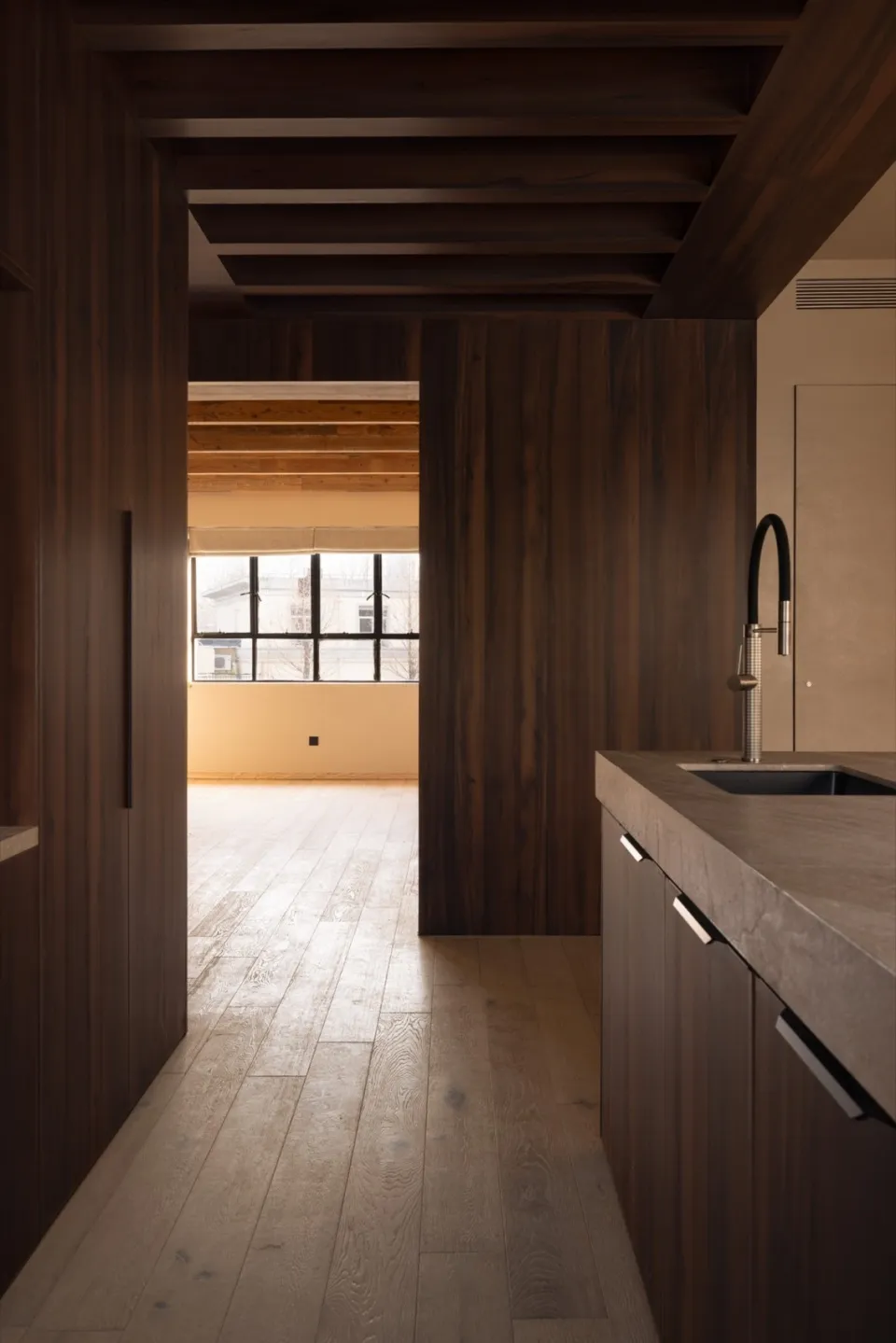 Modern kitchen interior with wooden flooring and cabinetry.