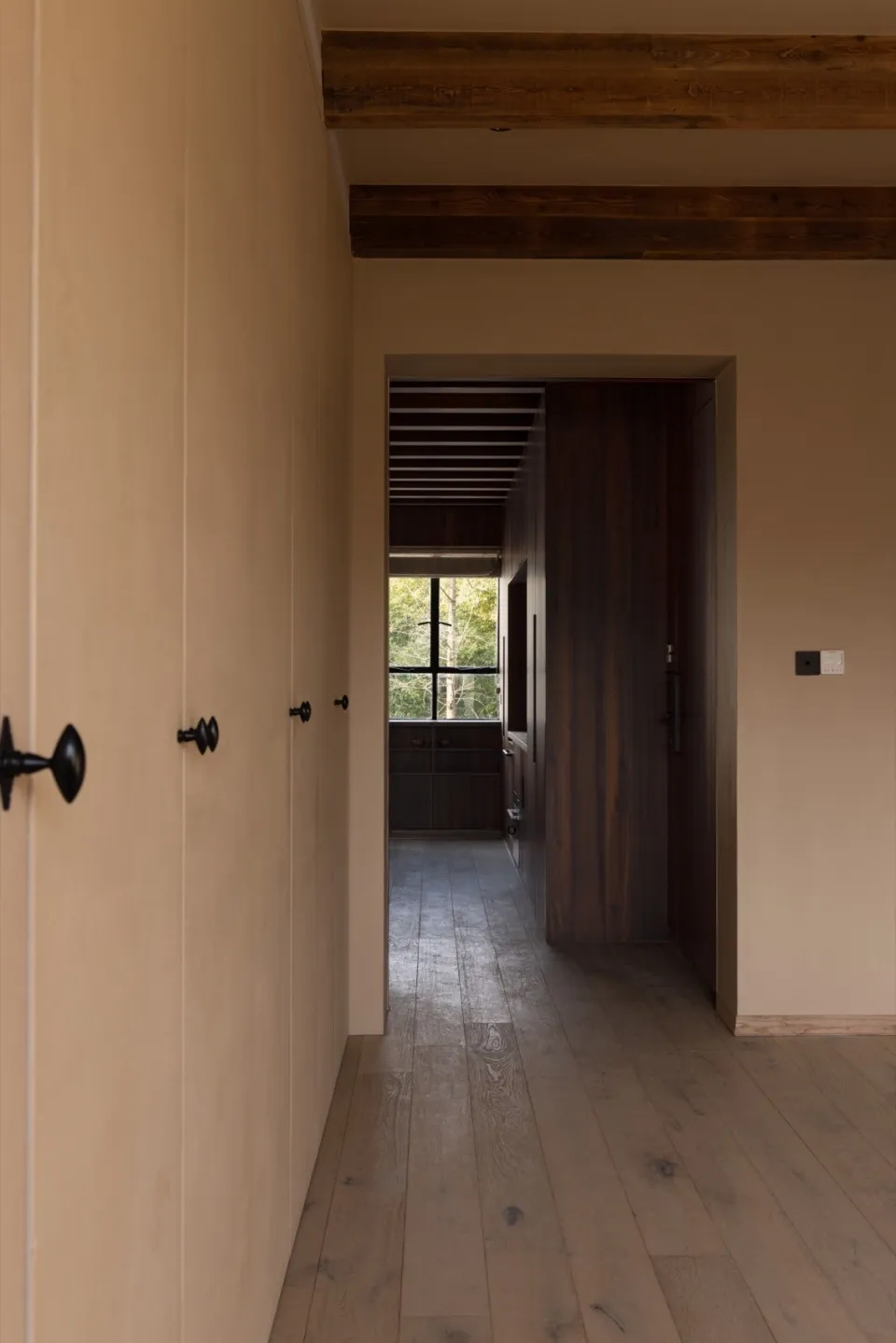 A modern minimalist interior with wooden flooring, concrete walls, and large windows.