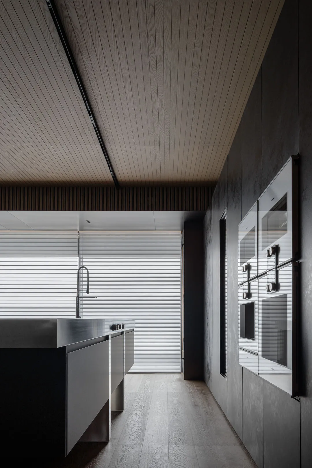 A modern residential kitchen features concrete countertops, wooden cabinets, and metal appliances.
