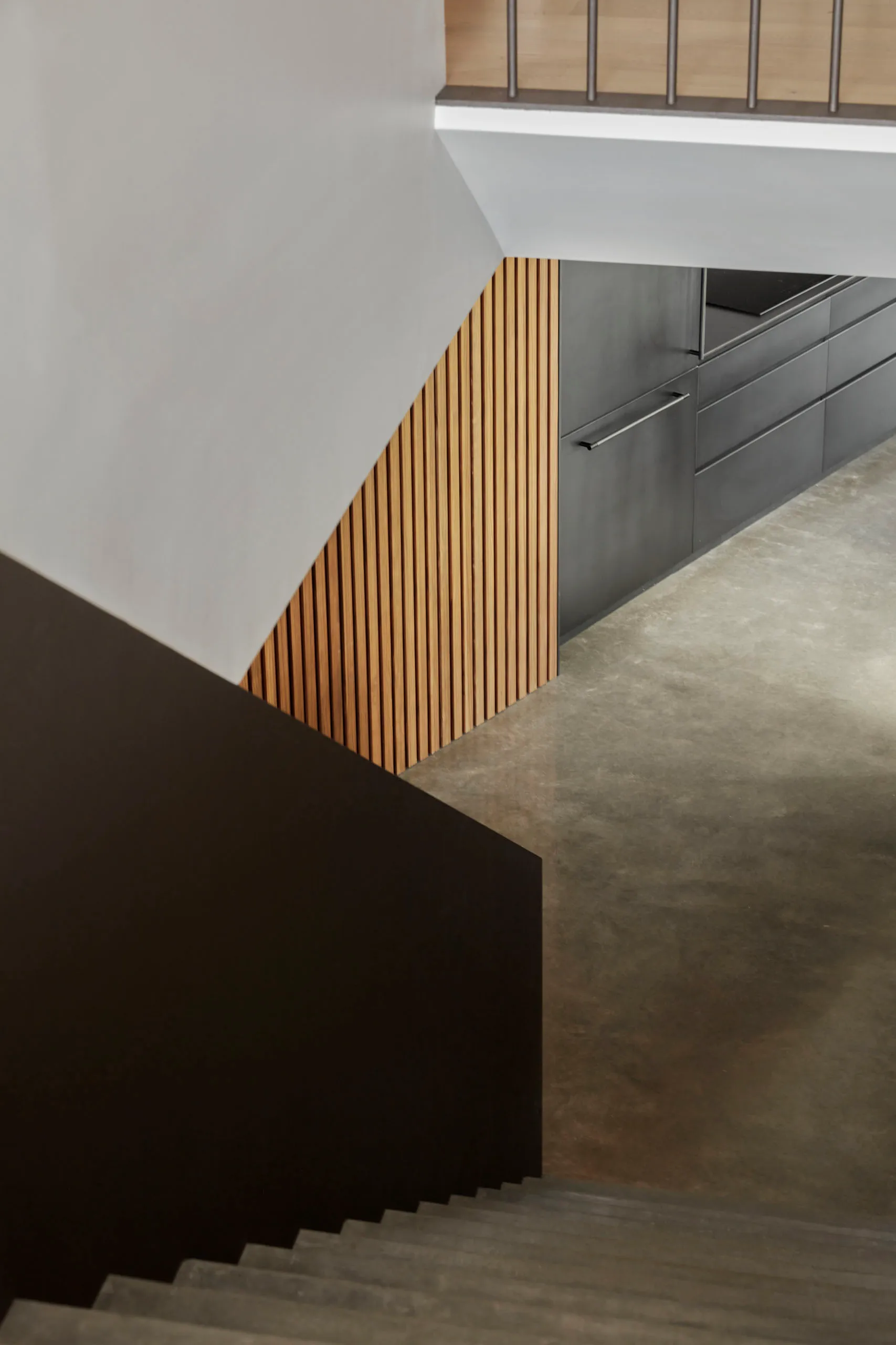 A modern kitchen with wooden paneling and dark concrete flooring.