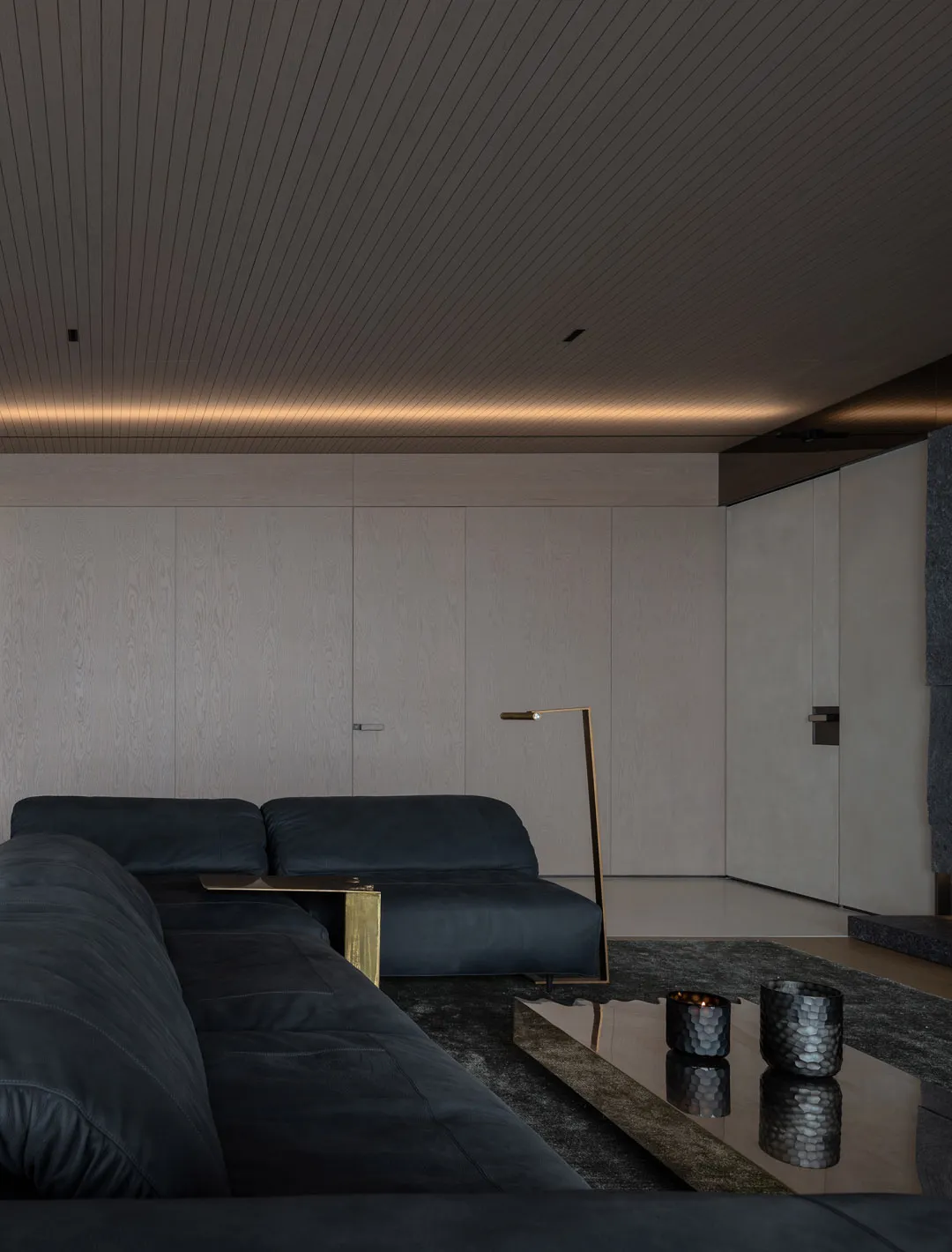 Modern living room featuring dark leather sofas and metal accents.